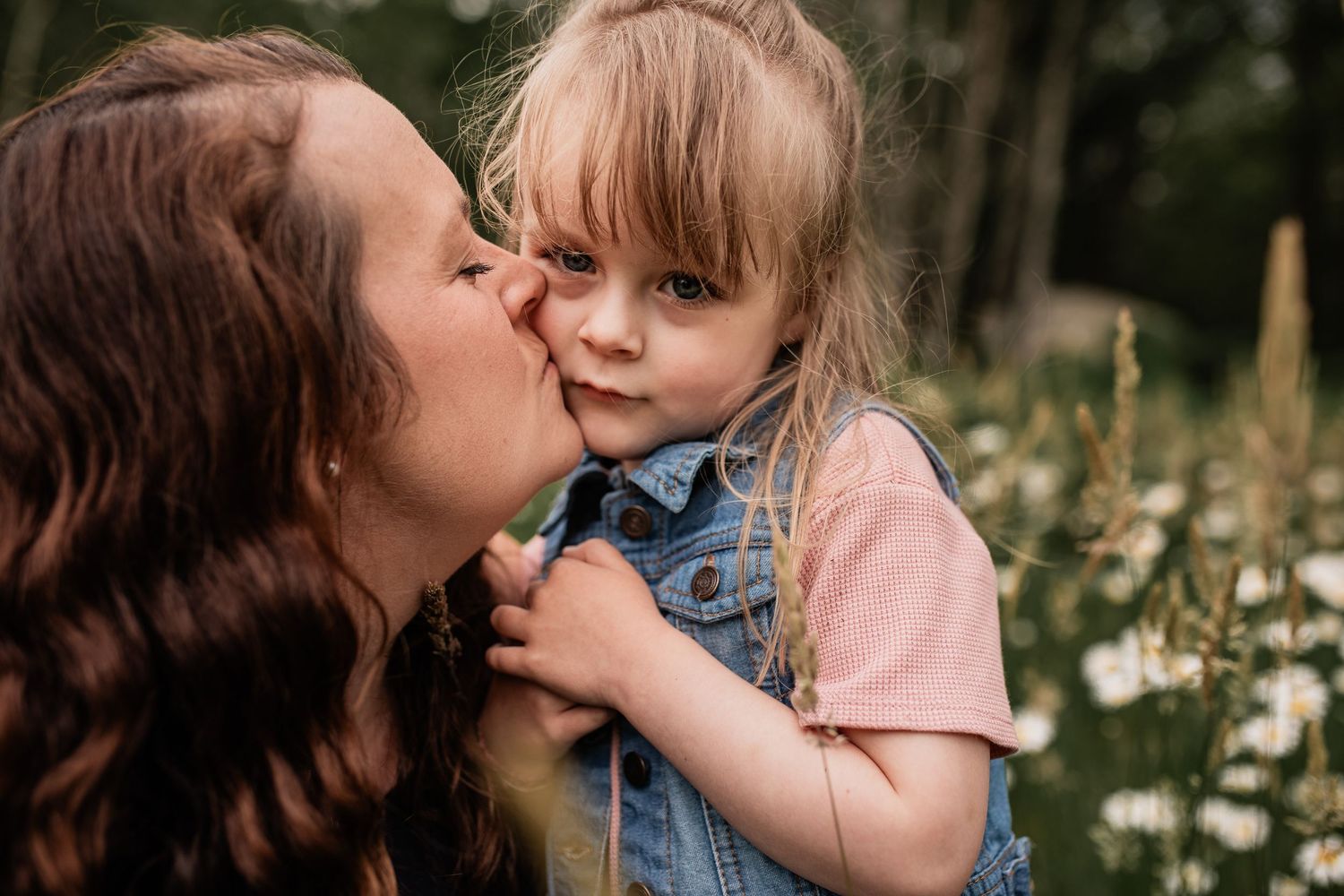 Sweet moment between parent and child in field of daisies.
