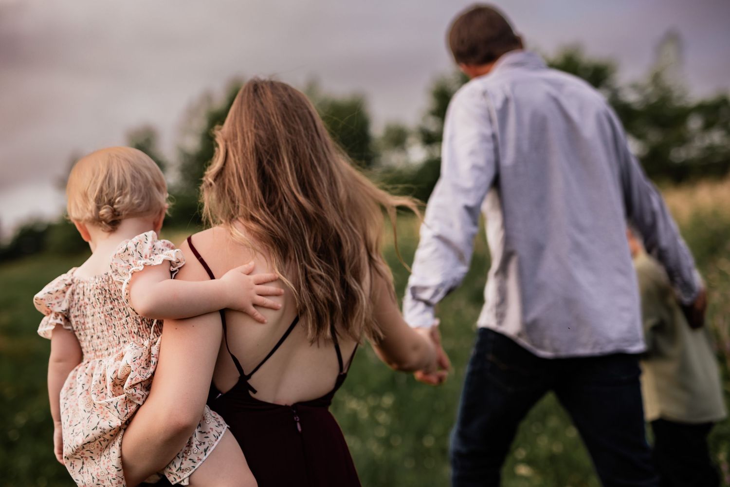 Family walking together through a wildflower meadow at sunset.
