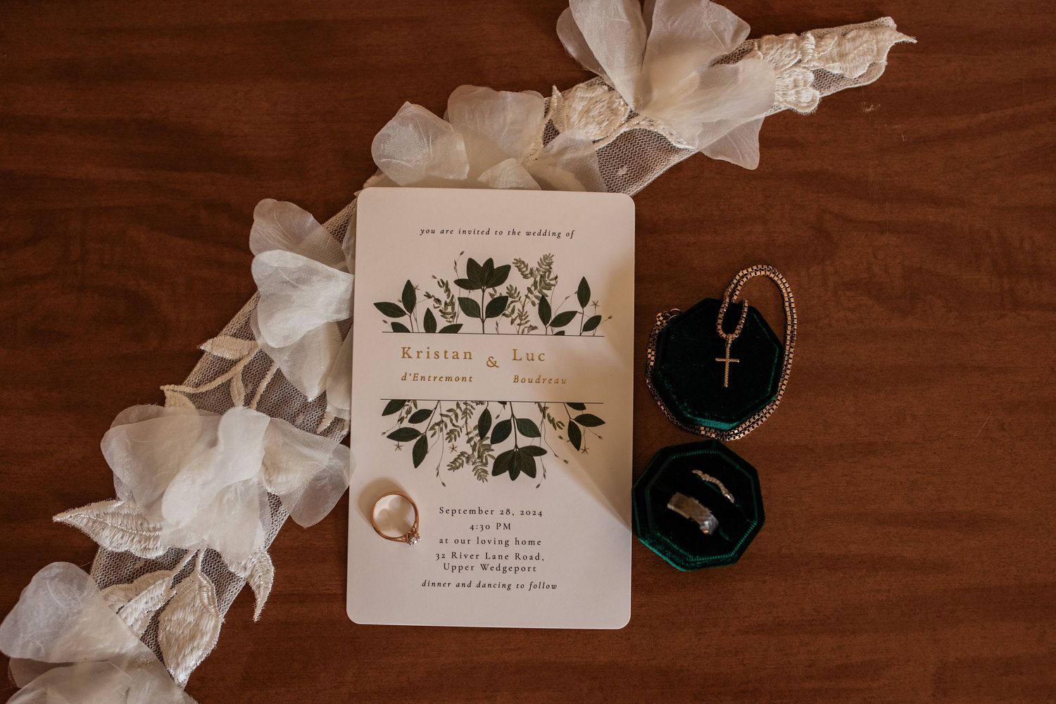Wedding invitation with floral design laid out with white ribbon and blue accessories.