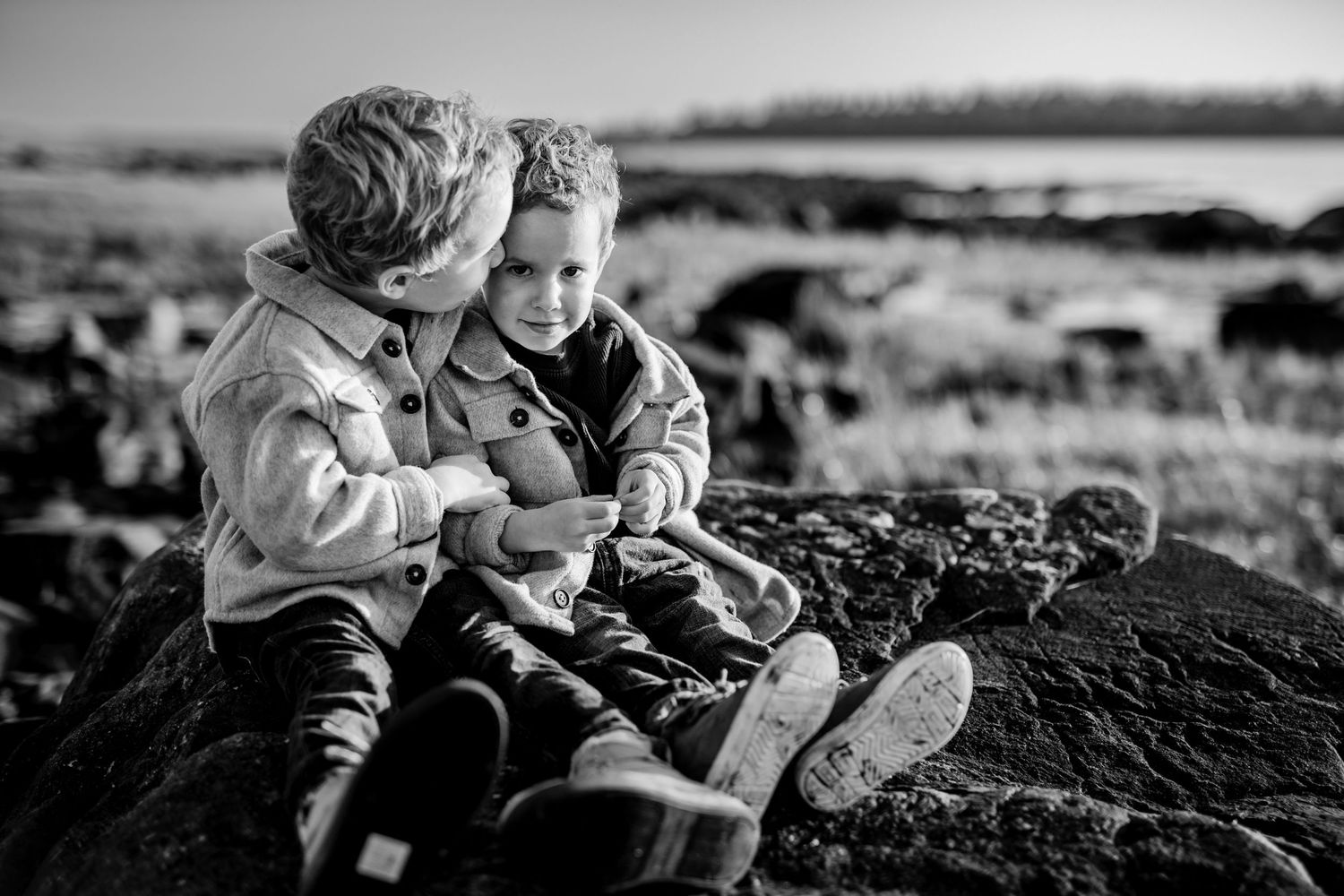A black and white capture of playful moments on rocky terrain at dusk.
