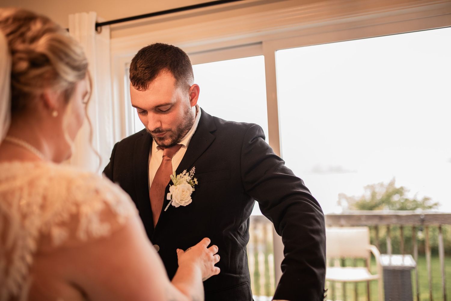 An intimate wedding moment captured by a window with natural light streaming in.