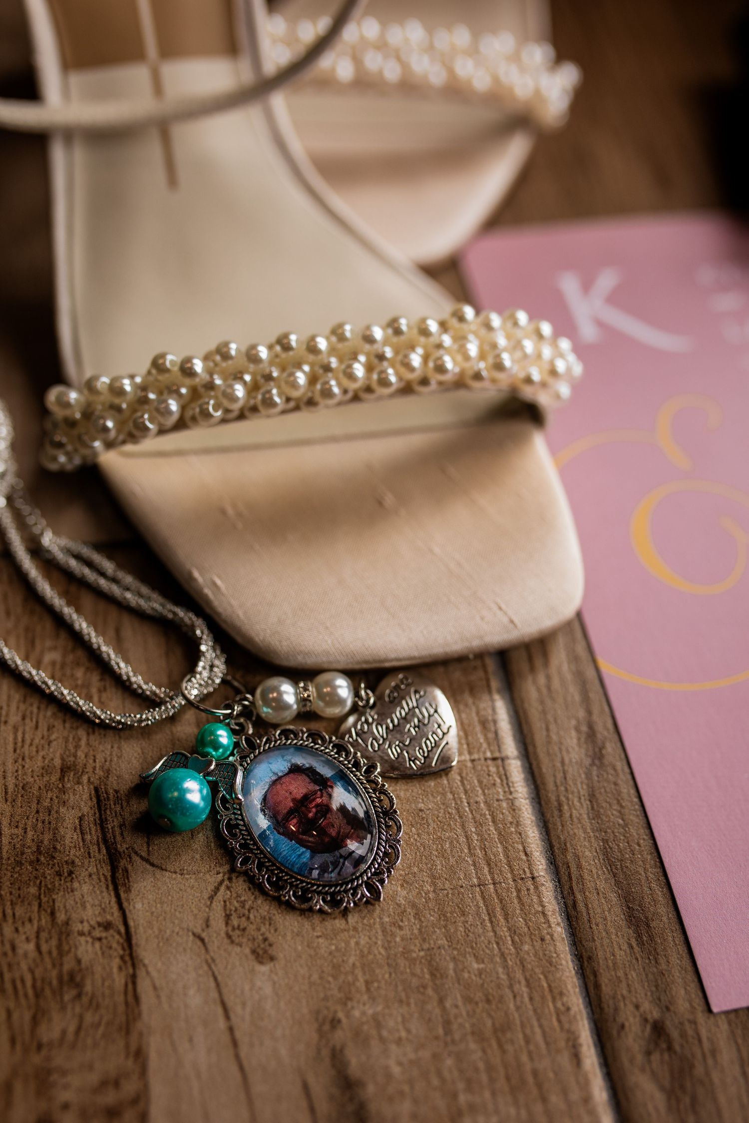 Vintage-style pearl necklace and emerald jewelry accessories displayed on wooden surface.
