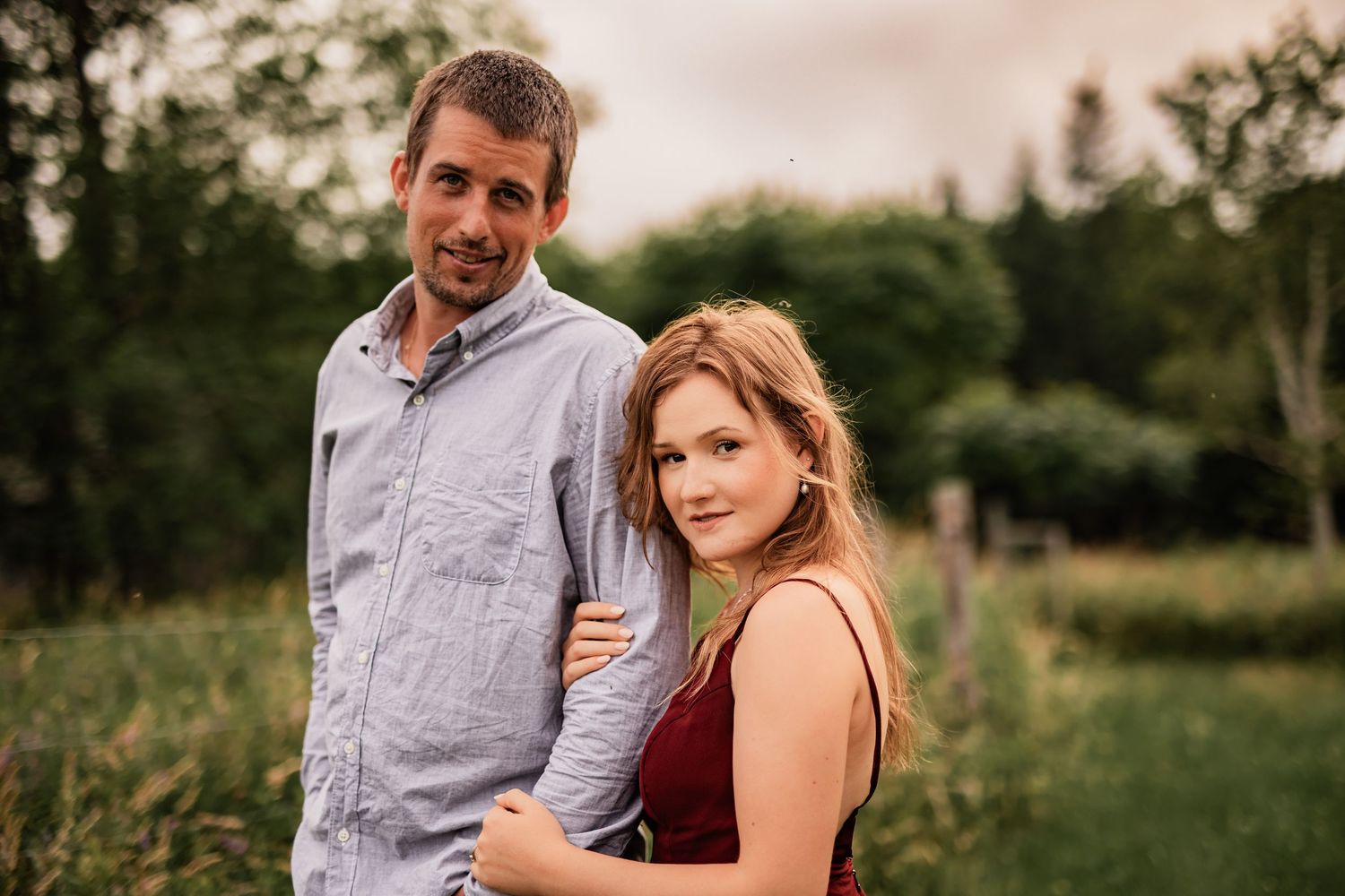 Romantic couple's portrait session in a natural meadow setting at golden hour.