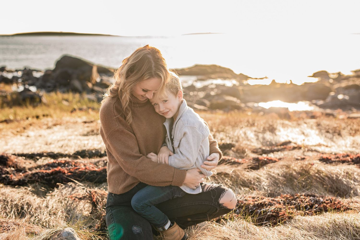 A heartwarming outdoor family photoshoot session captured at golden hour on rocky terrain.