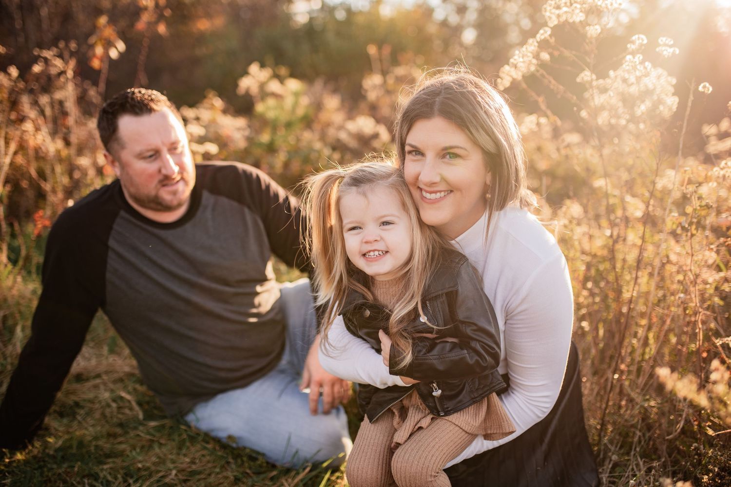 A candid moment captured during sunset as a group sits together in golden-lit wild grass.