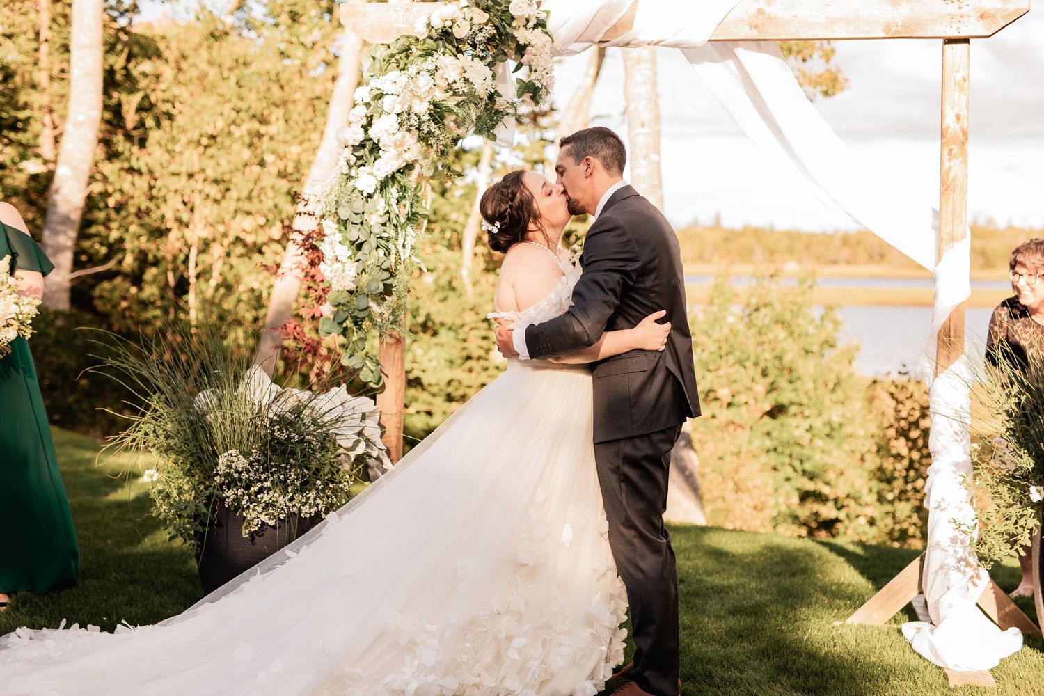Couple shares an intimate moment at their outdoor garden wedding ceremony surrounded by greenery and natural light.