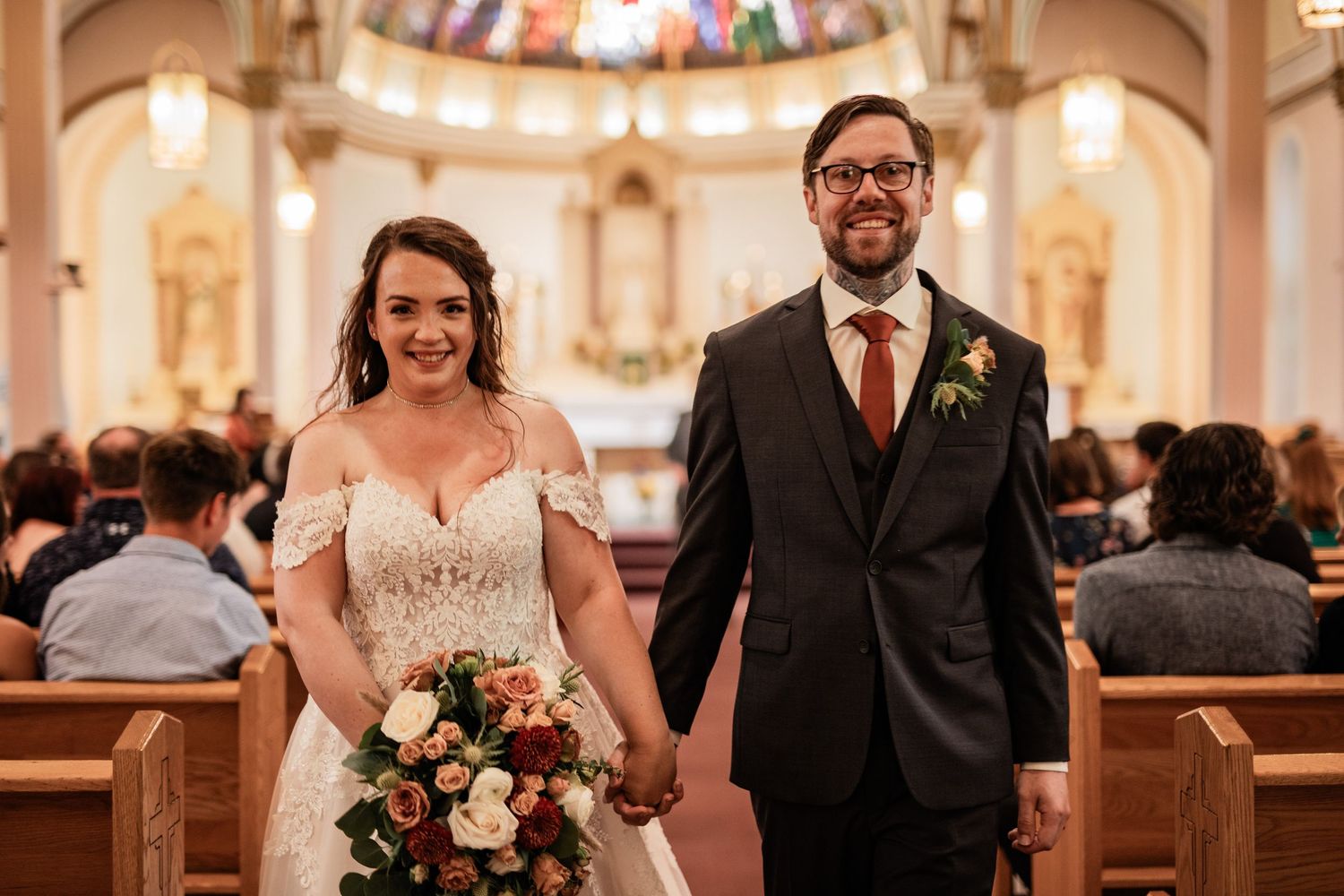 Elegant church wedding ceremony with couple standing at altar holding floral bouquet.