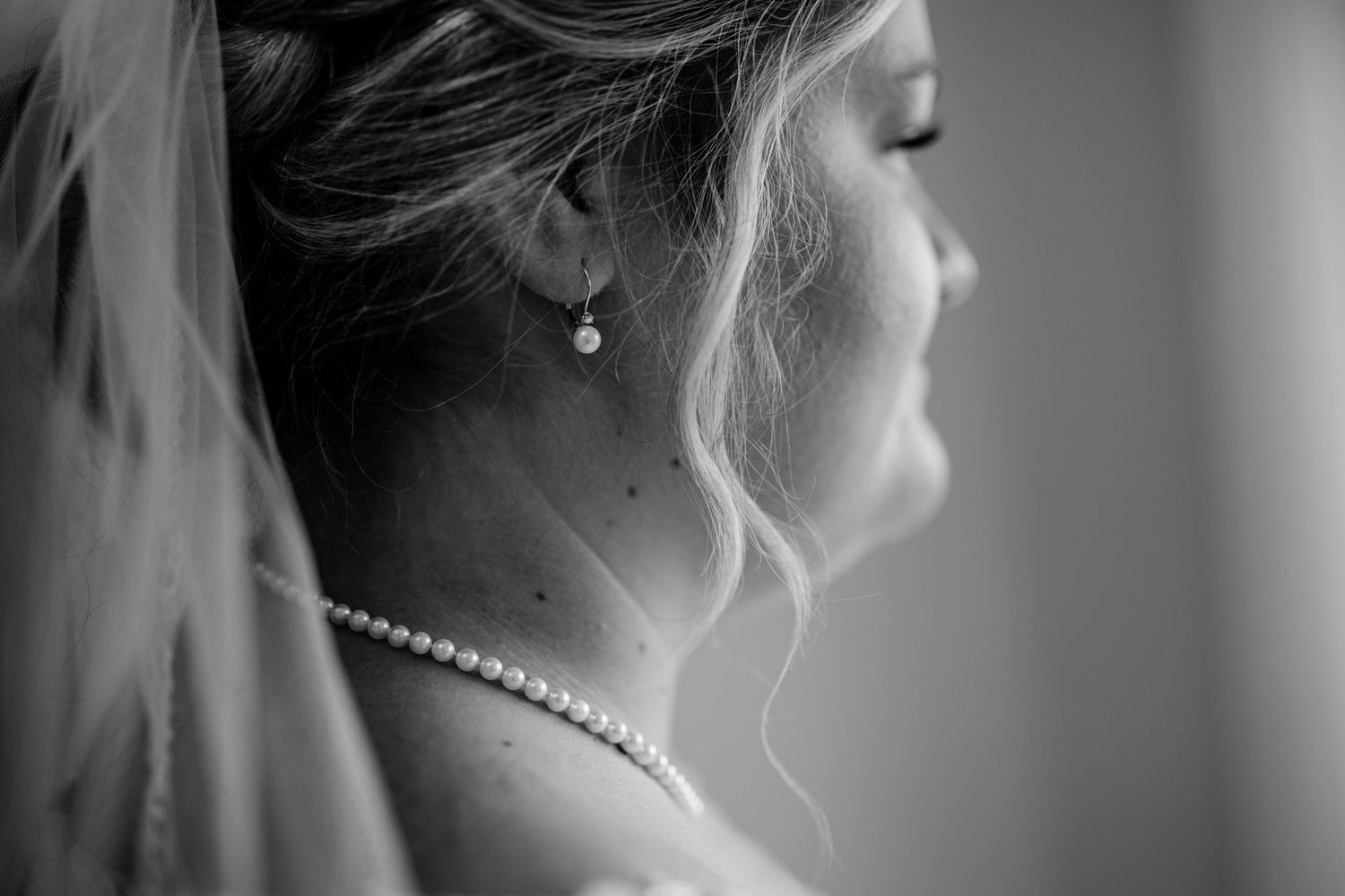 Close-up black and white profile shot showing pearl necklace and veil details.