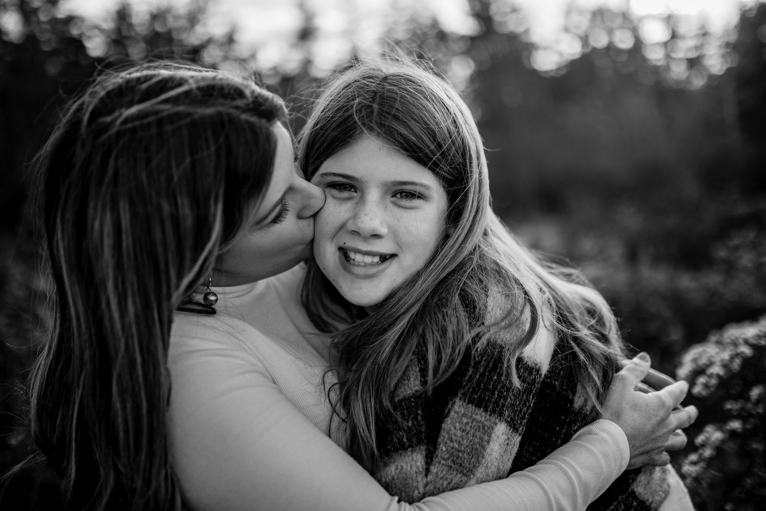 A tender black and white moment shared between two people embracing outdoors.