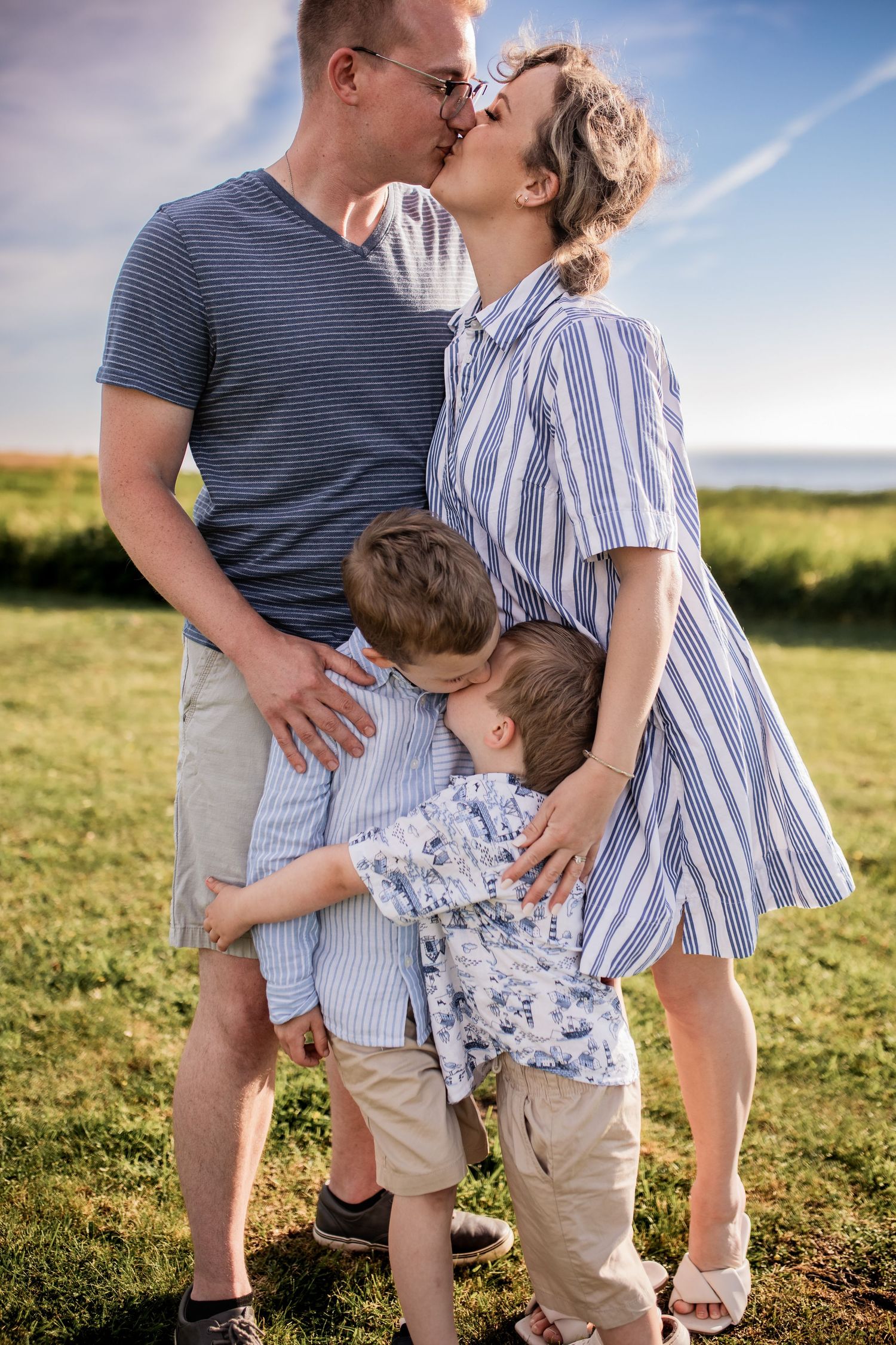 Family sharing an intimate moment together outdoors in summer attire.