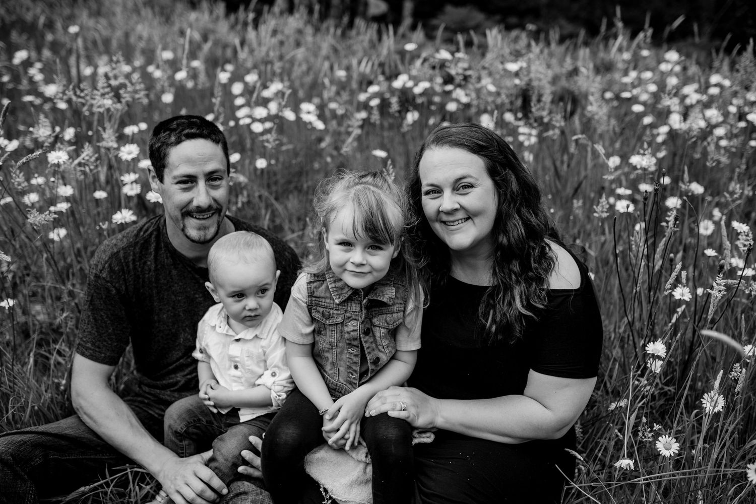 Black and white family portrait in field of wild daisies.