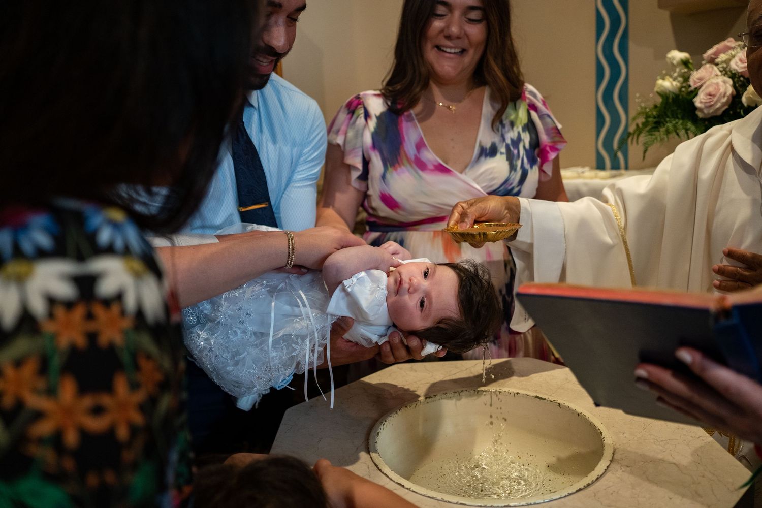 A baptism ceremony with water being poured over an infant's head during a religious service.