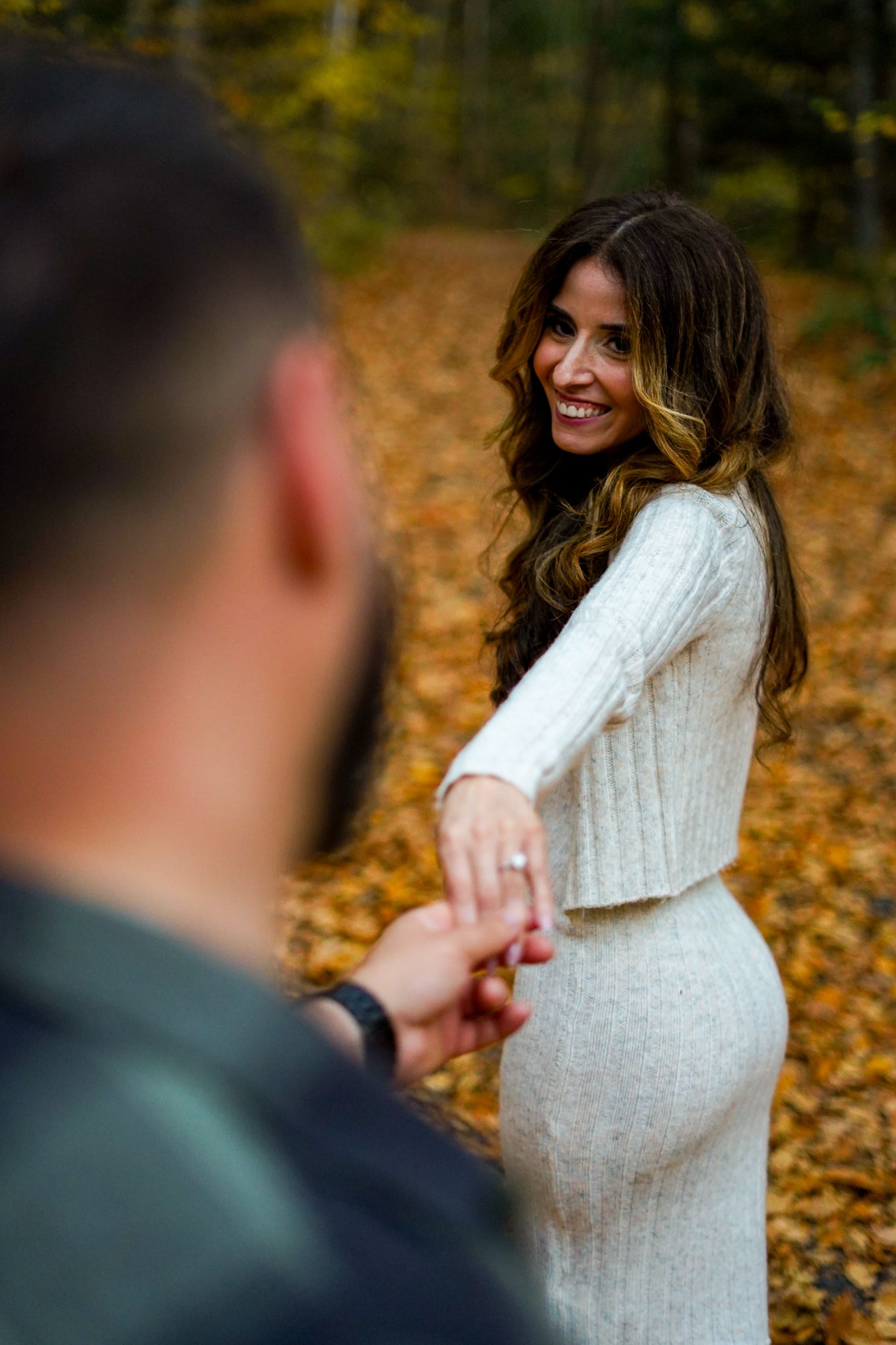 A romantic autumn engagement photo with fallen leaves in the background.