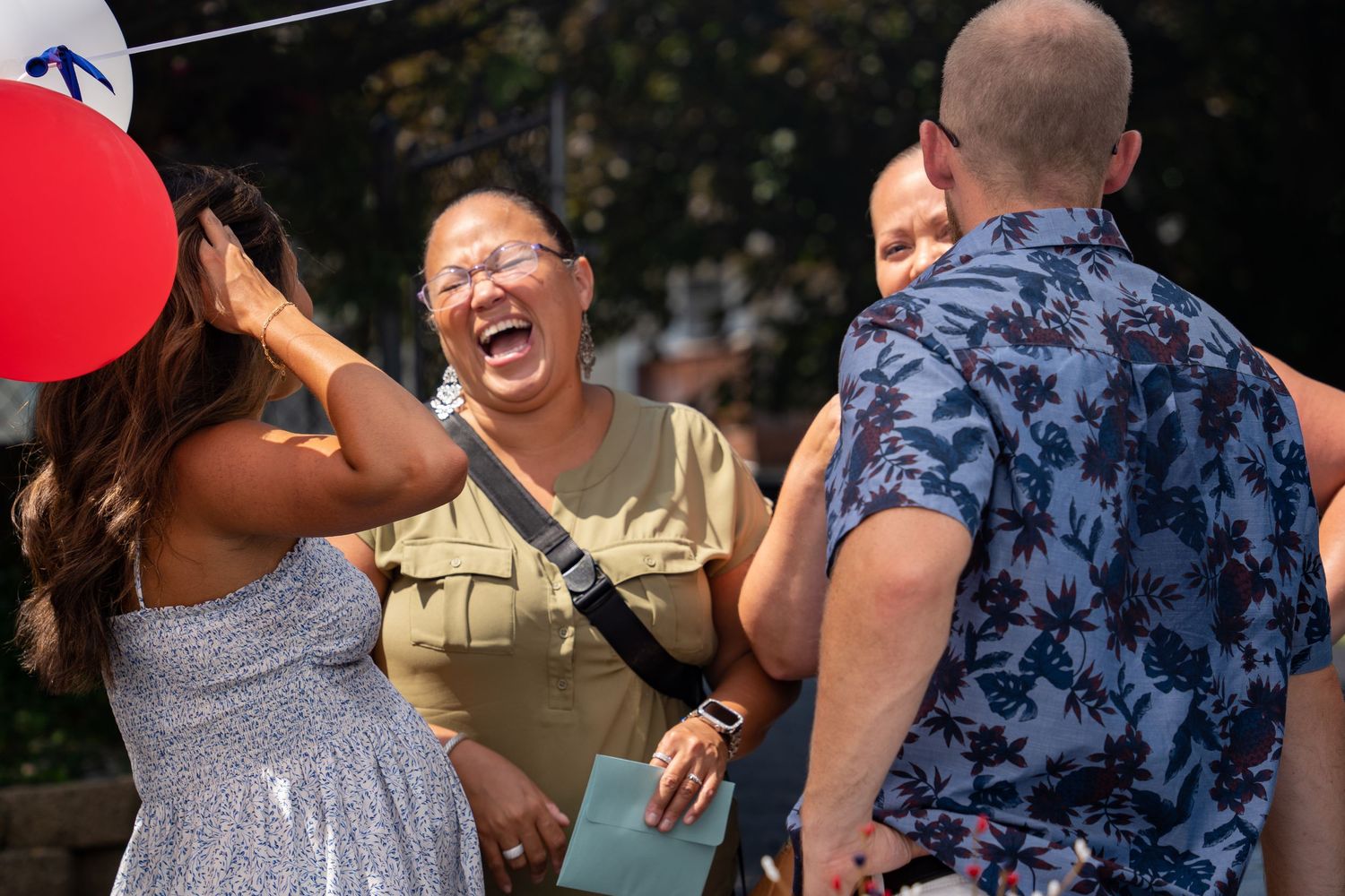A group sharing laughter at an outdoor celebration with patriotic decorations.