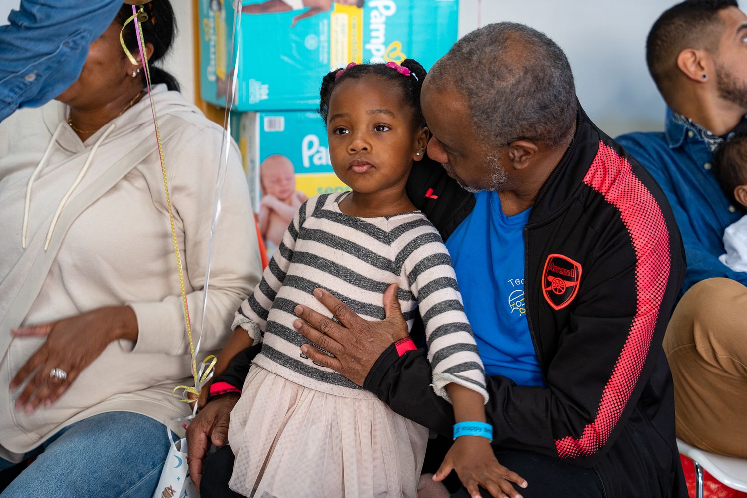 A sweet moment of a grandfather whispering into his granddaughter's ear at a birthday party