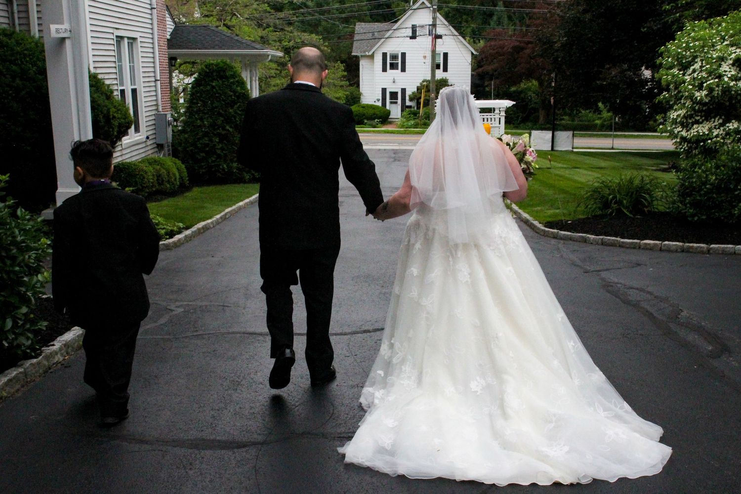 A couple walks down a residential street after their wedding ceremony.