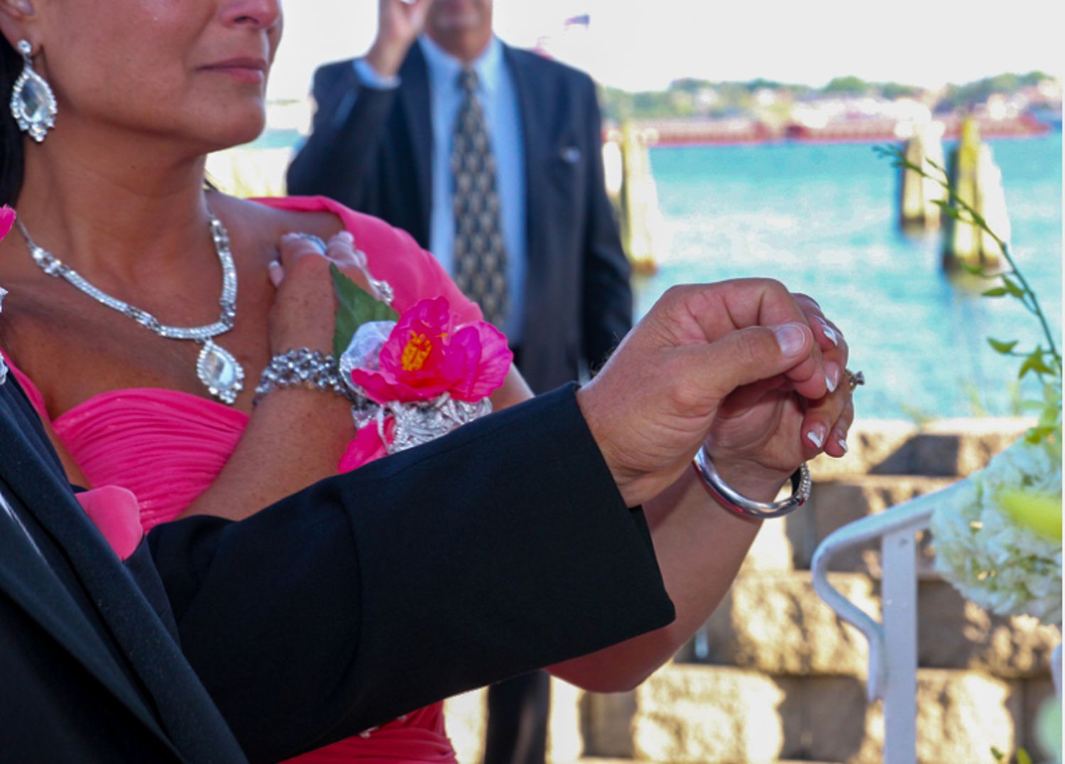 A person in a bright pink dress with silver jewelry at an outdoor waterfront event.