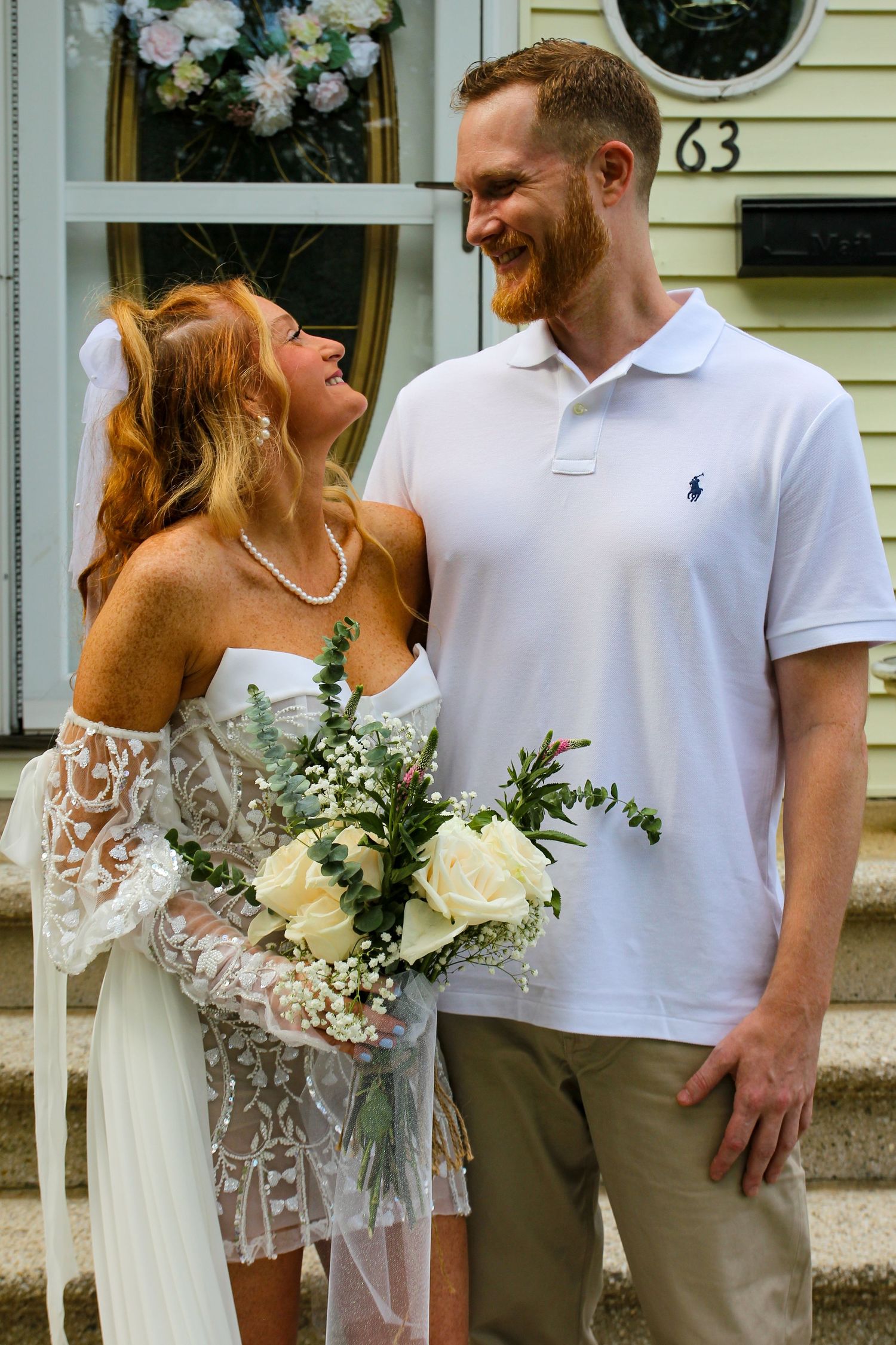 A couple shares a joyful moment together on their wedding day outside a house.