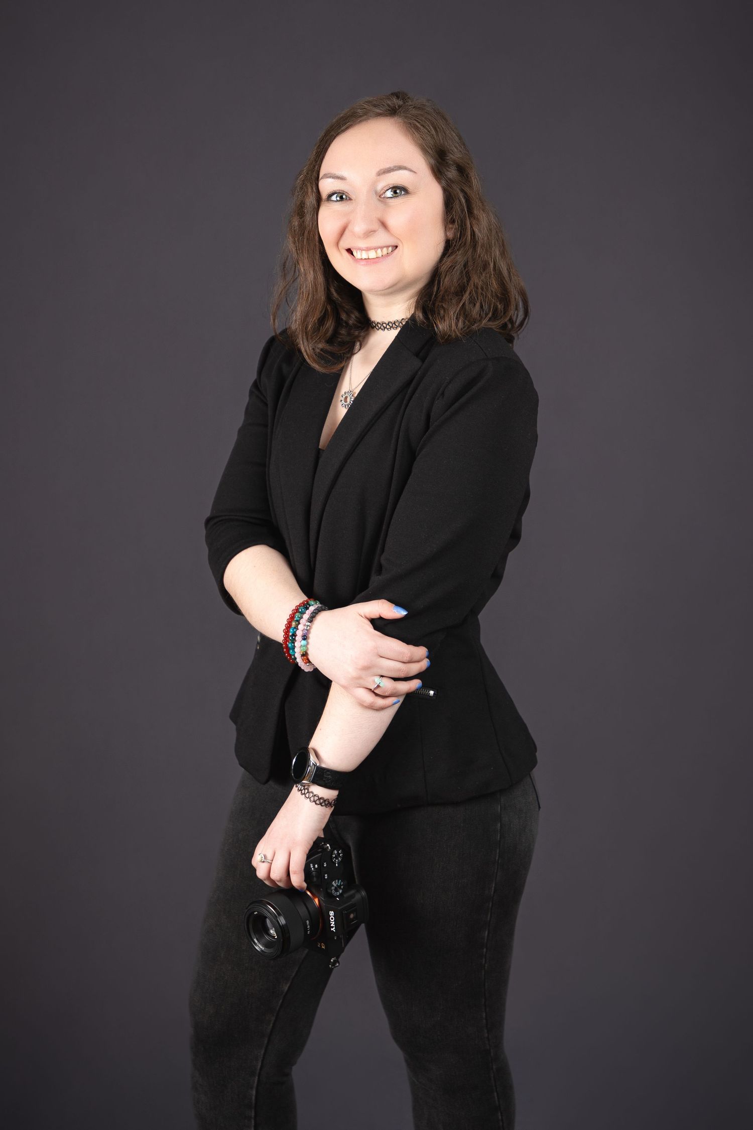 Professional portrait of a photographer in black business attire against dark background.