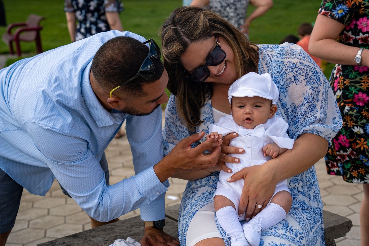 People gathered around a baby at an outdoor celebration event.