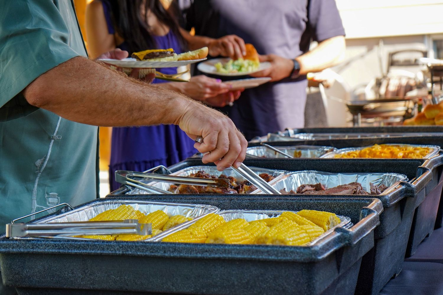 Buffet service line with colorful food dishes in stainless steel catering trays.