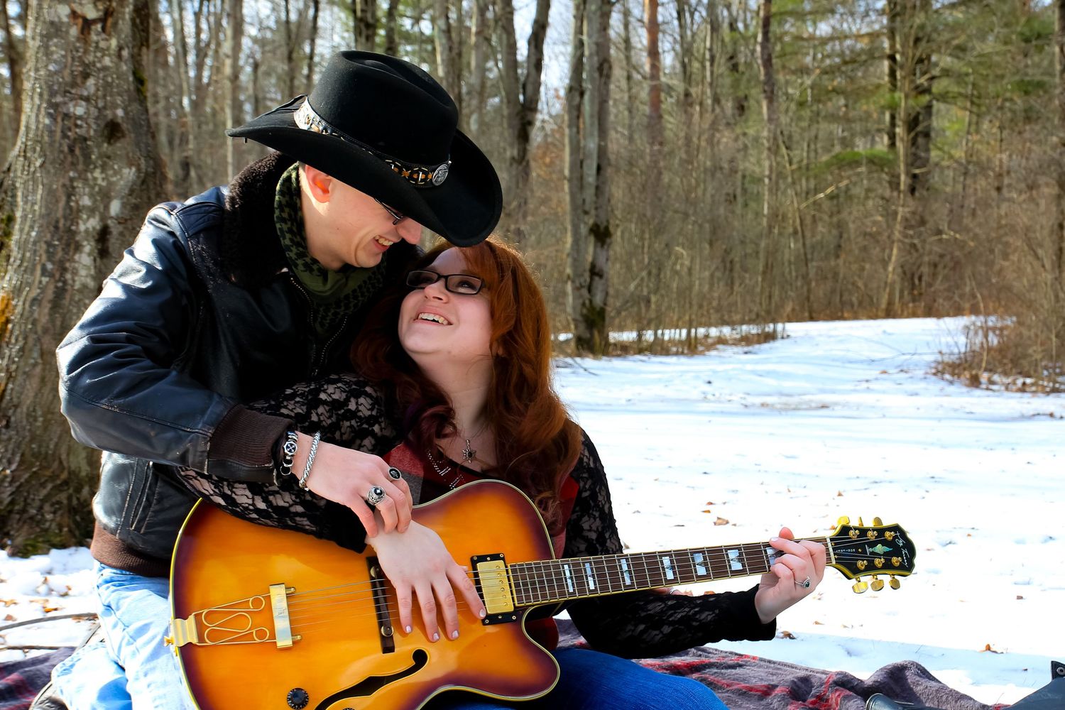 Winter scene with acoustic guitar on snowy blanket in forest setting.