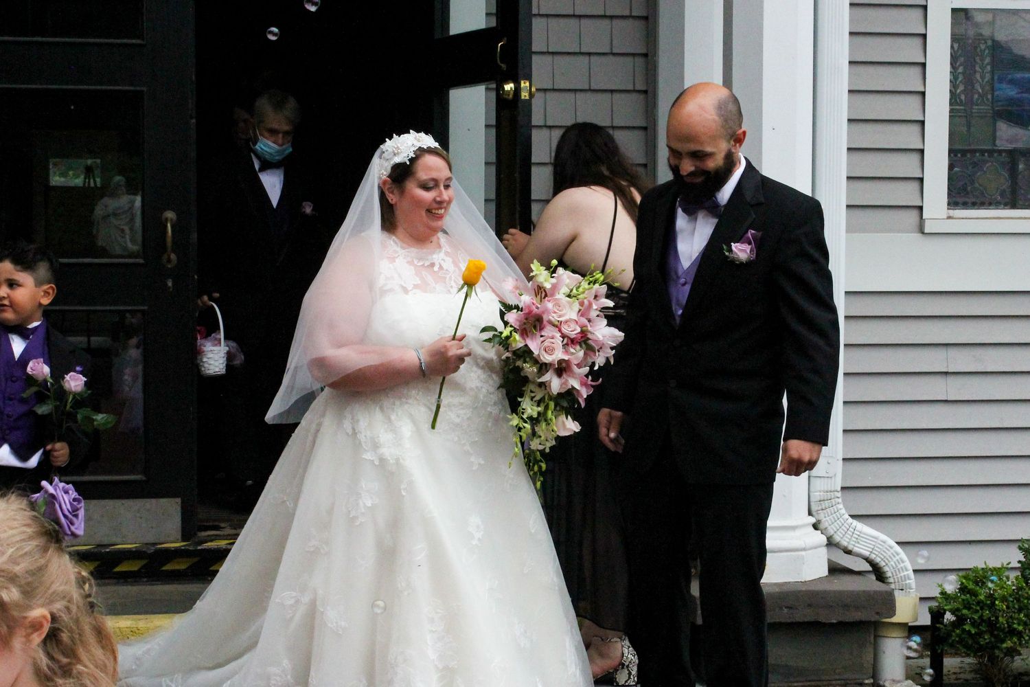 A couple shares a moment together after their wedding ceremony outside a gray house.