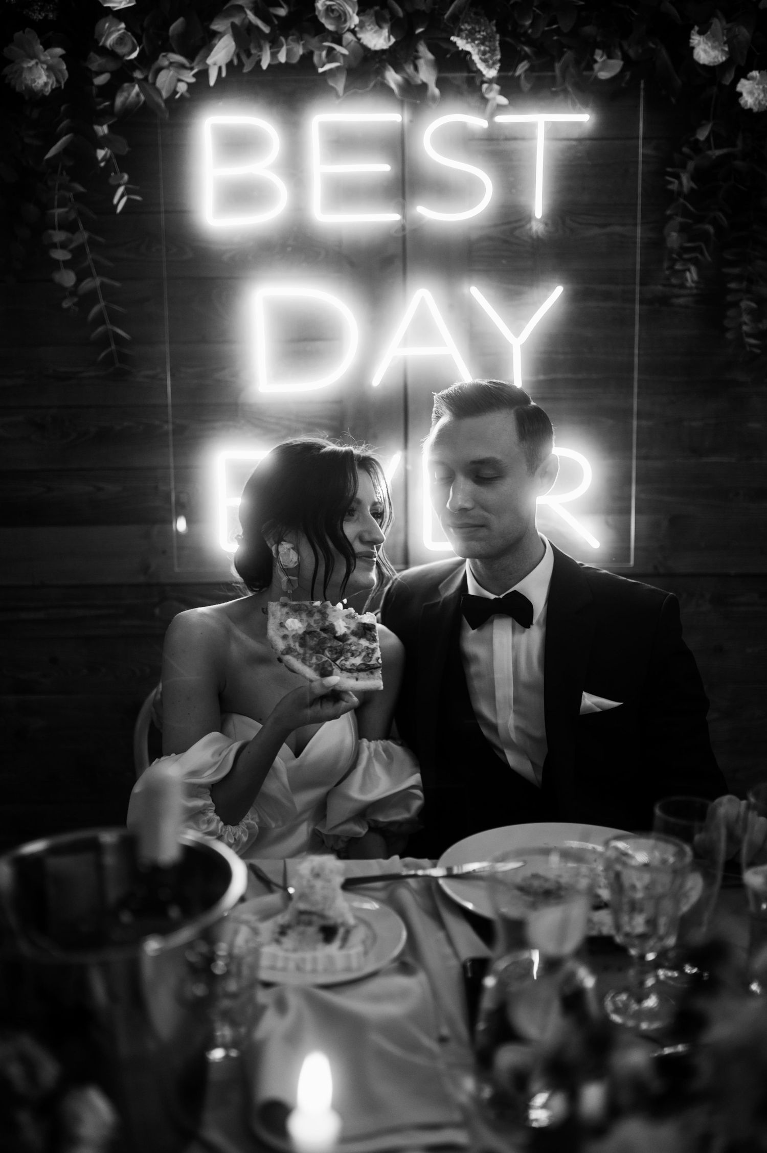 Panna młoda z kawałkiem pizzy – humorystyczny moment przy neonowym napisie „Best Day Ever”.
