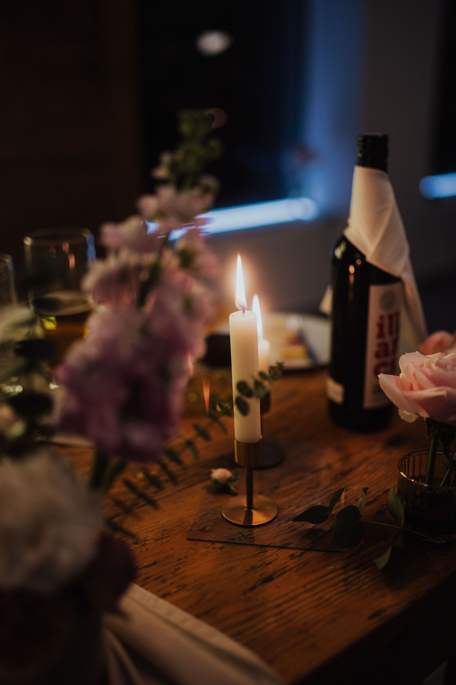 Romantyczne dekoracje ślubne na stole państwa młodych, świece, wino i różowe, sezonowe kwiaty.