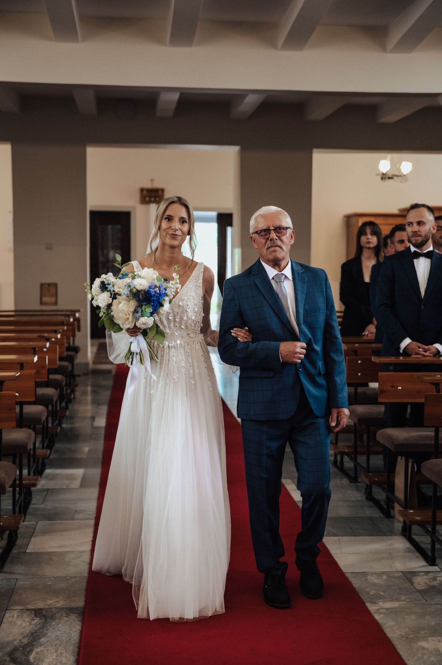Wejście panny młodej na ceremonię ślubną do kościoła, prowadzona przez dziadka. Reportaż ślubny Gdańsk.