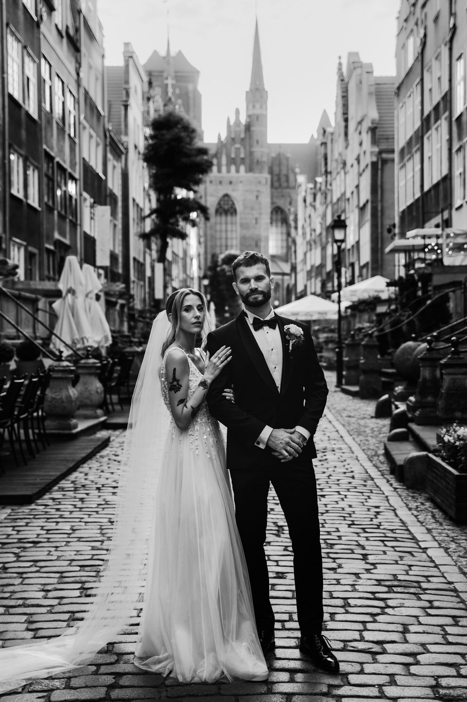 Sesja ślubna na starym mieście na ulicy Mariackiej w Gdańsku o zachodzie słońca. Czarno-biała fotografia pary młodej.