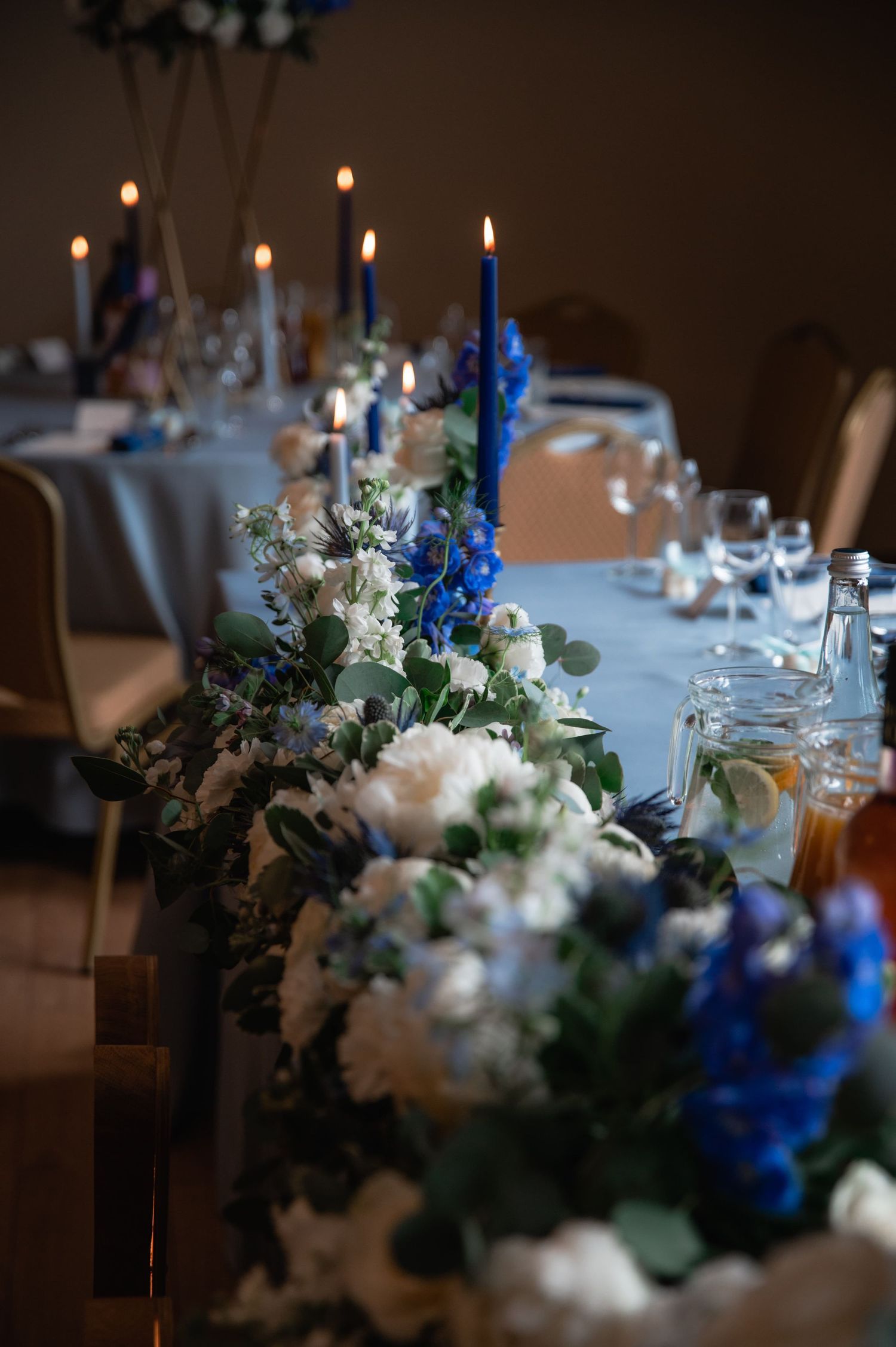 Romantyczne dekoracje weselne w Gdańsku – biało-niebieskie kwiaty i świece na stołach w restauracji Ołowianka