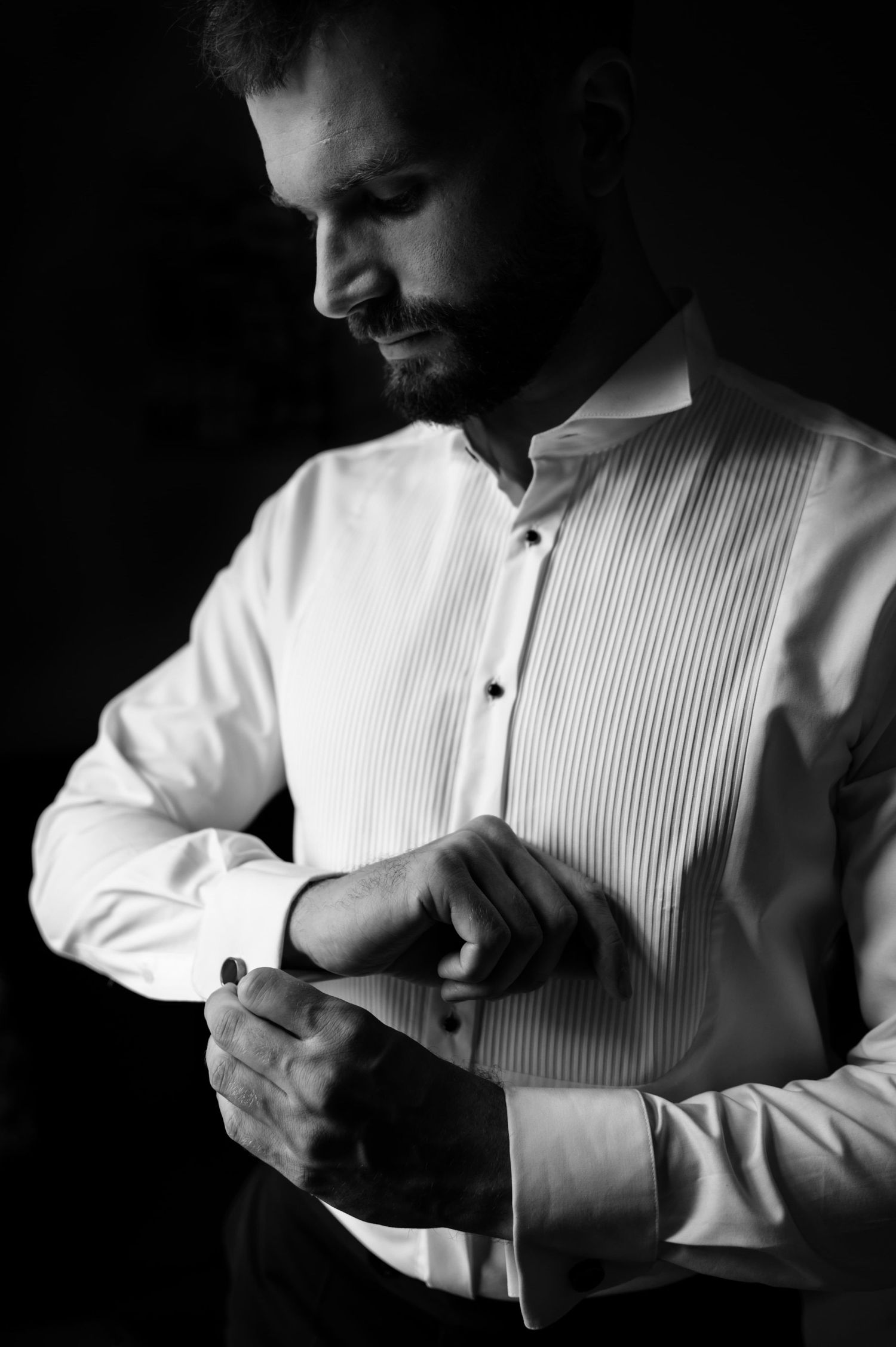 Pan młody zapina mankiety eleganckiej koszuli podczas przygotowań do ślubu w Gdańsku – portret w naturalnym świetle.