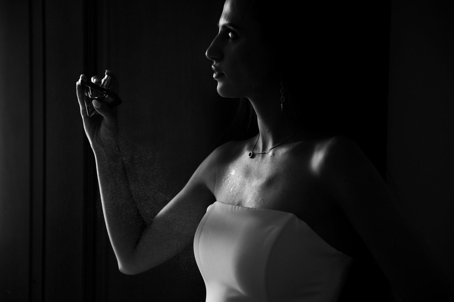 Nastrojowy portret panny młodej w cieniu, aplikującej perfumy – elegancja i cisza przed ślubem