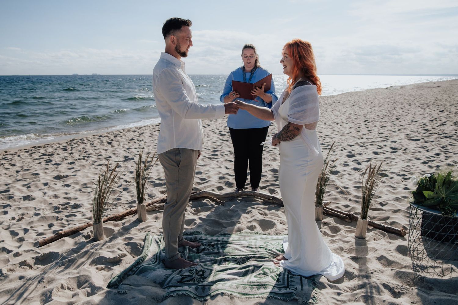 Romantyczny ślub cywilny na plaży w Helu – para młoda składa przysięgę małżeńską boso na piasku, z morzem w tle i minimalistyczną dekoracją.