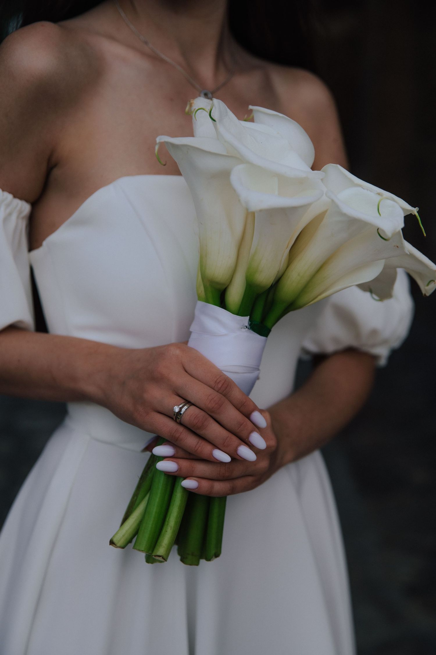 Minimalistyczny portret bukietu kalii w dłoniach panny młodej – detal eleganckiego ślubu w Scopello