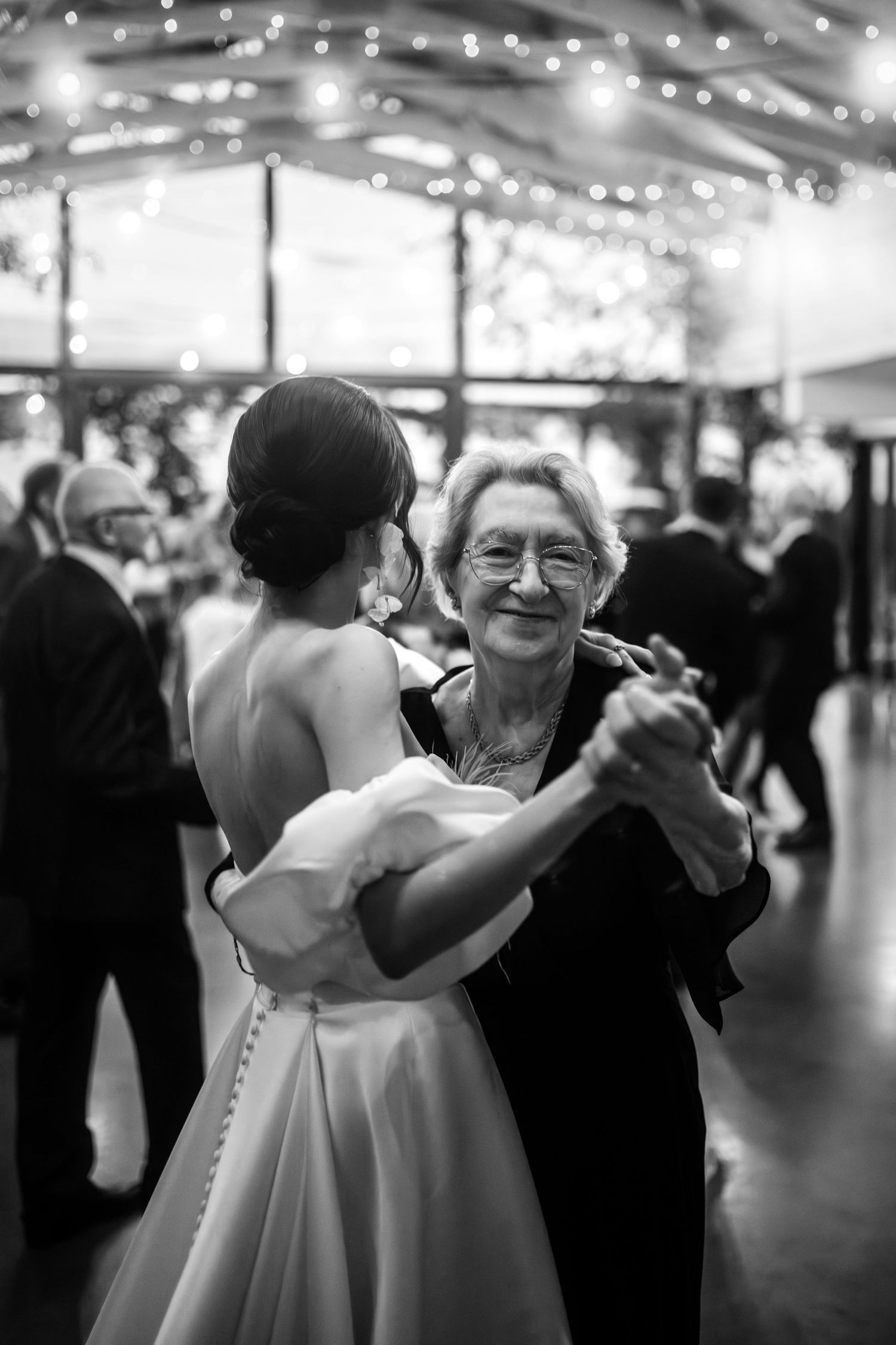 Panna młoda w eleganckiej sukni tańczy z babcią w czarno-białym ujęciu — wzruszający moment rodzinnej bliskości podczas wesela w Willi Słone