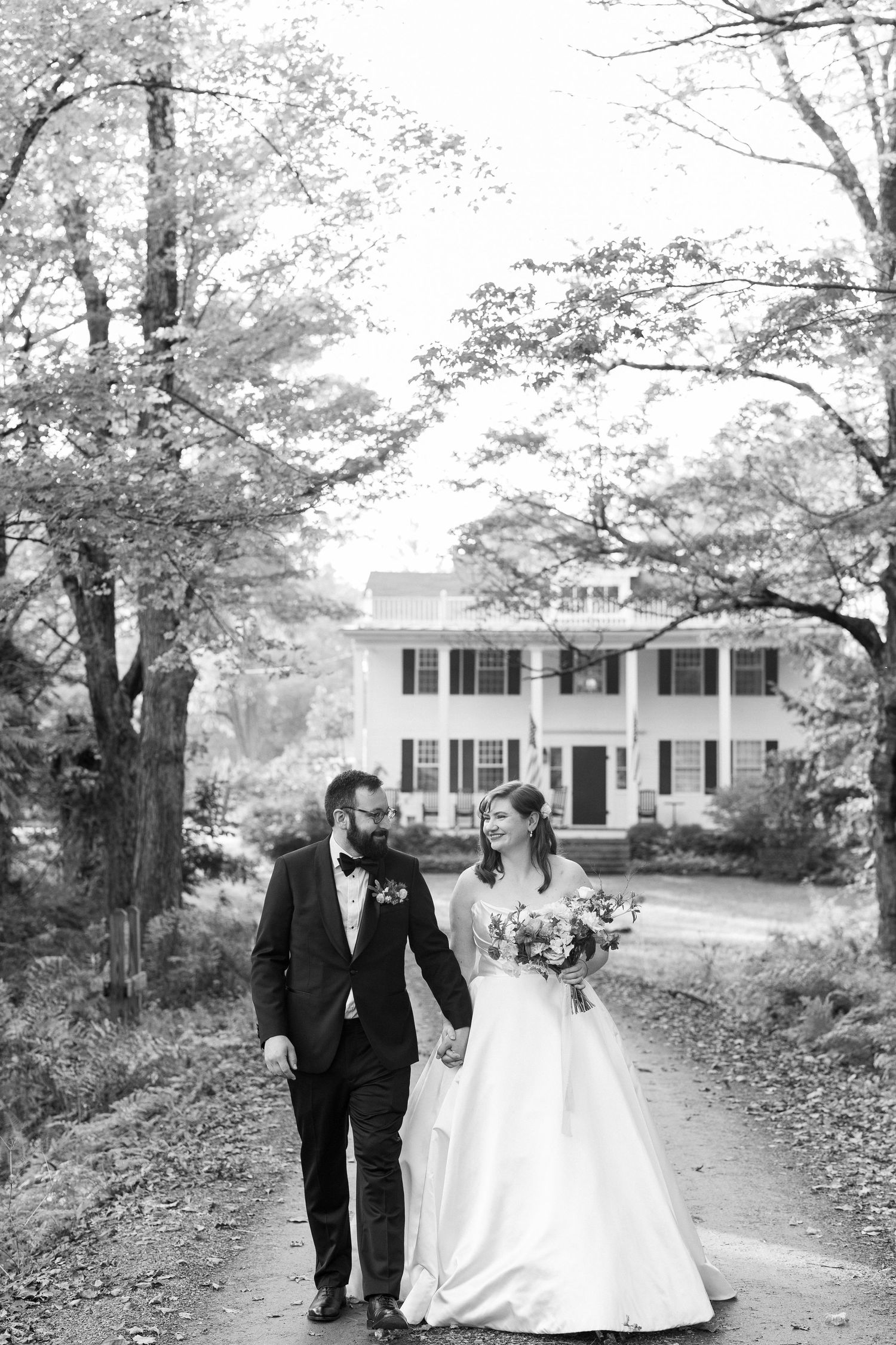 Couple walks hand in hand towards photographer in front of the Inn at Weathersfield in Vermont