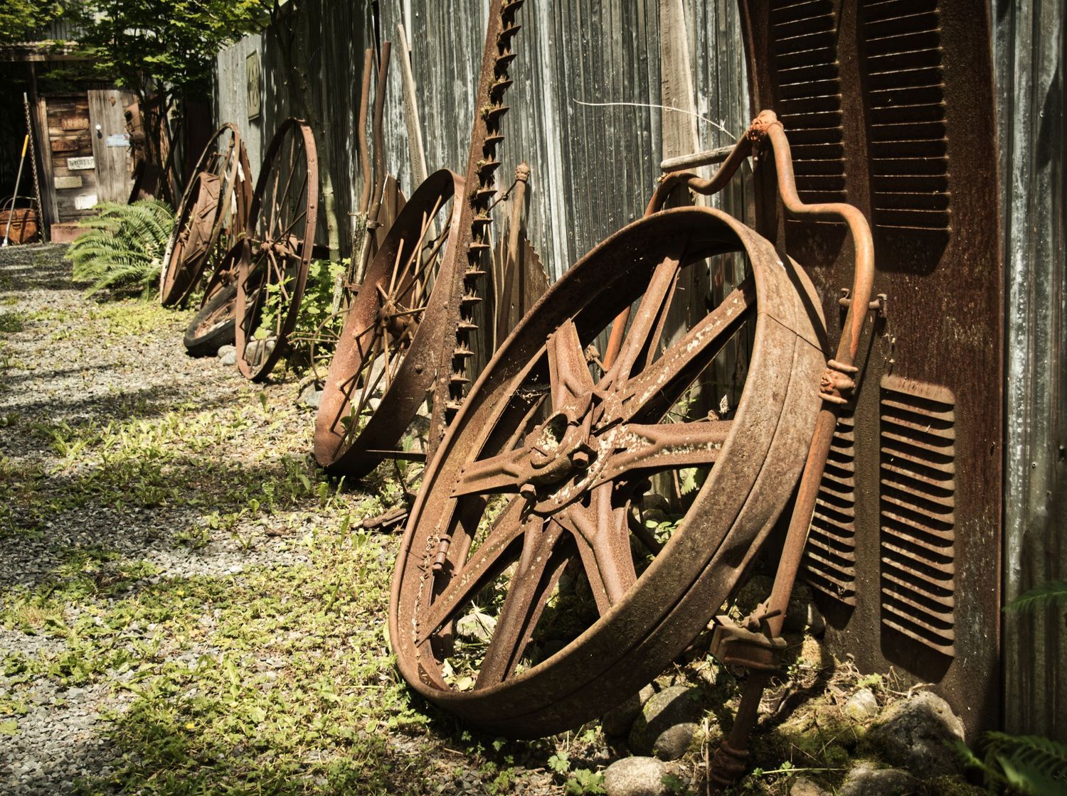 The photo depicts a rustic scene with aged, rusty pulleys leaning against the weathered wooden planks of an old barn.