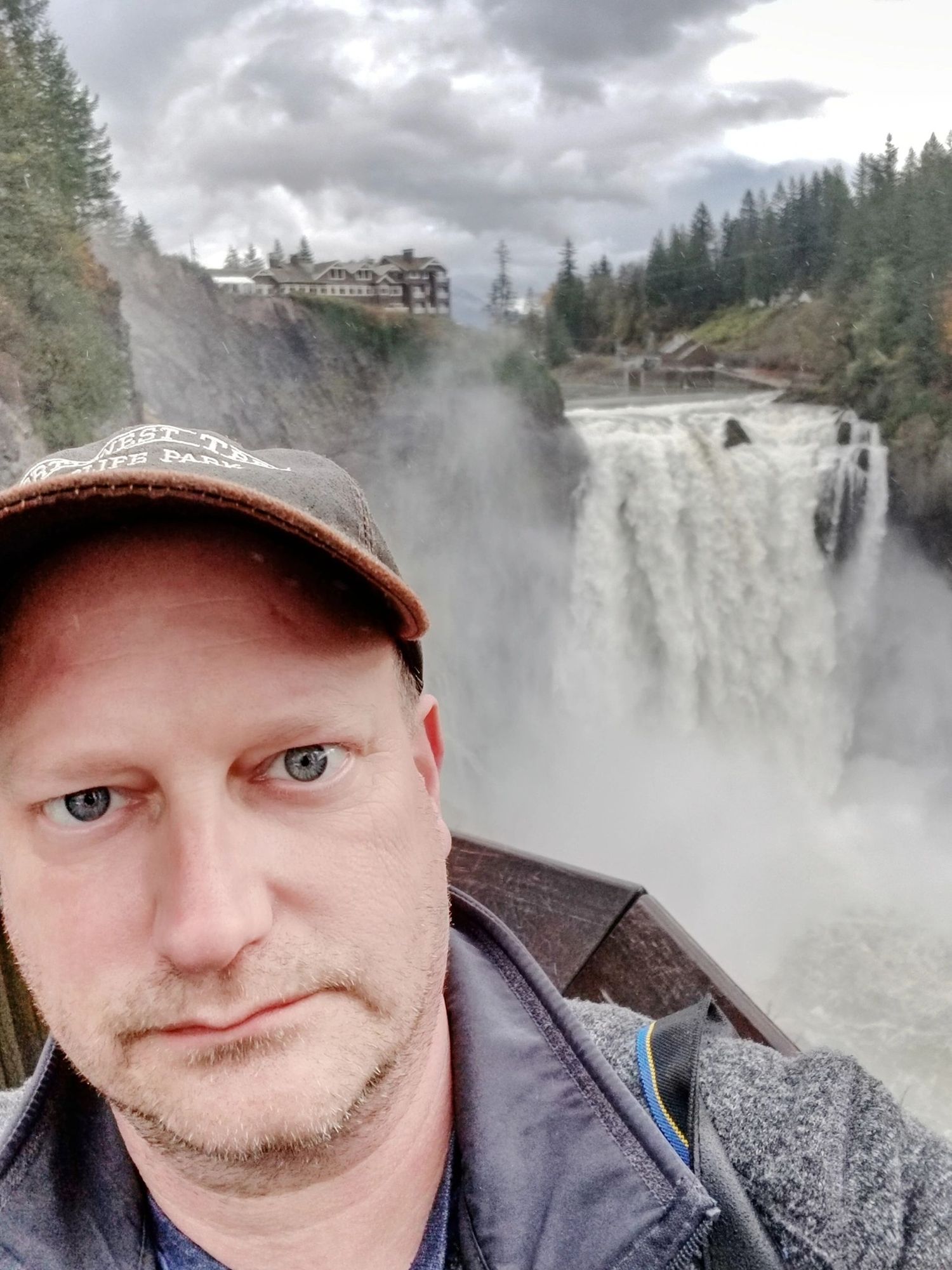 an incredibly handsome male photographer in front of a massive waterfall