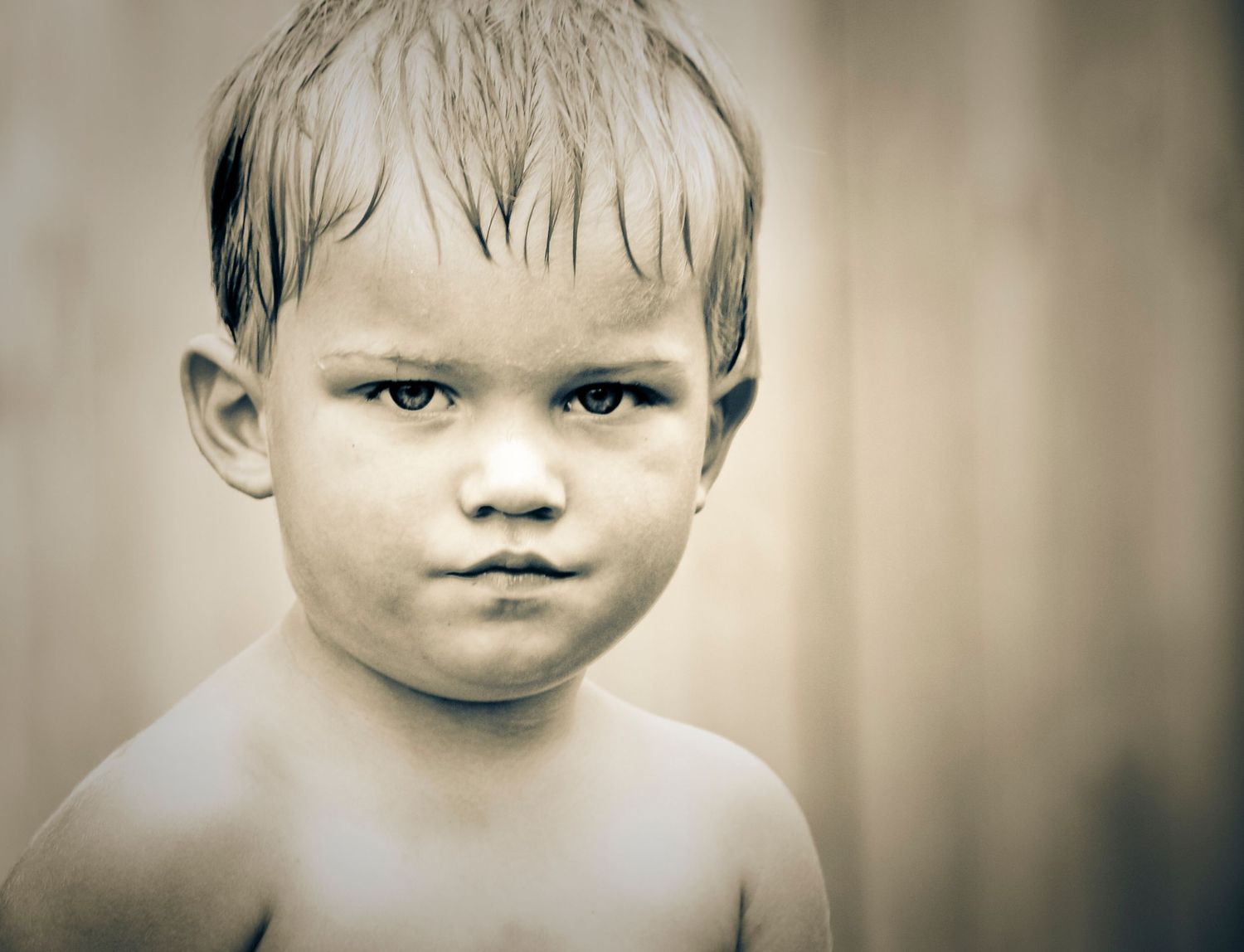 a young boy, wet from playing in water.