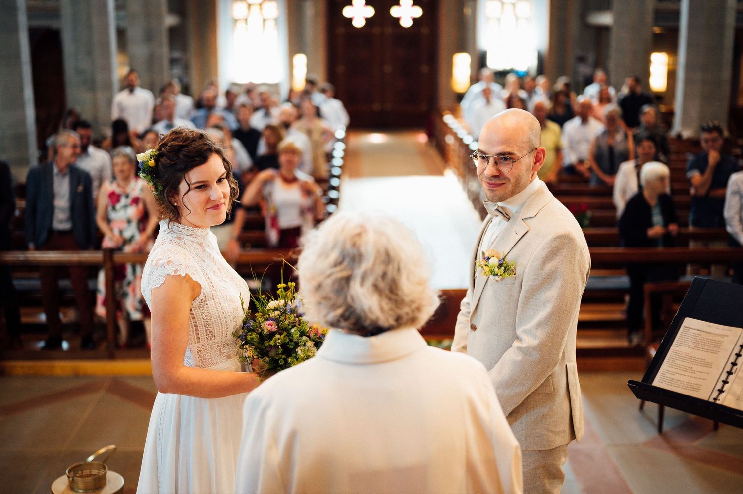 Wedding ceremony taking place inside a traditional church with guests in attendance.