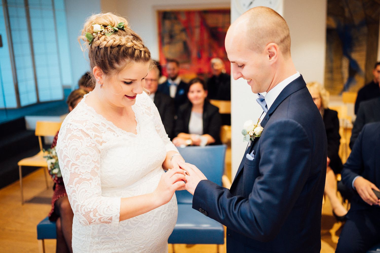 An intimate wedding ceremony moment showing rings being exchanged indoors.