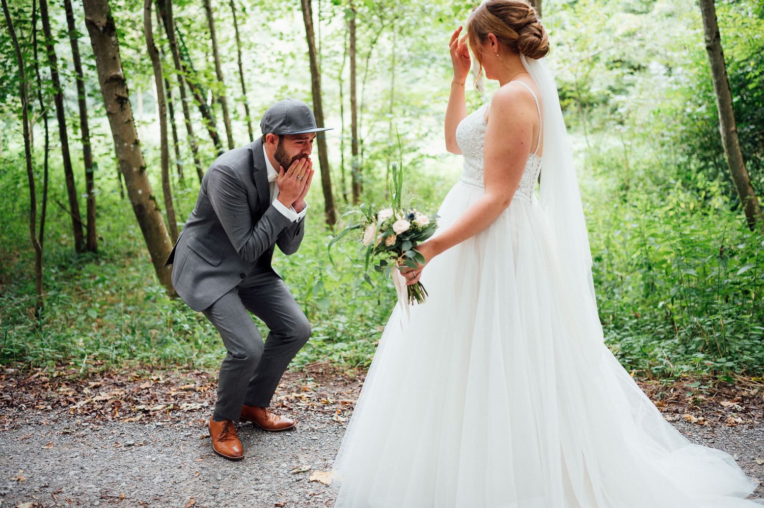 A playful wedding moment captured on a forest path with a couple in traditional wedding attire.