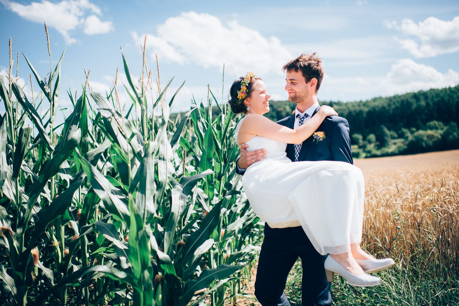 Wedding couple posing playfully in a cornfield on their special day.