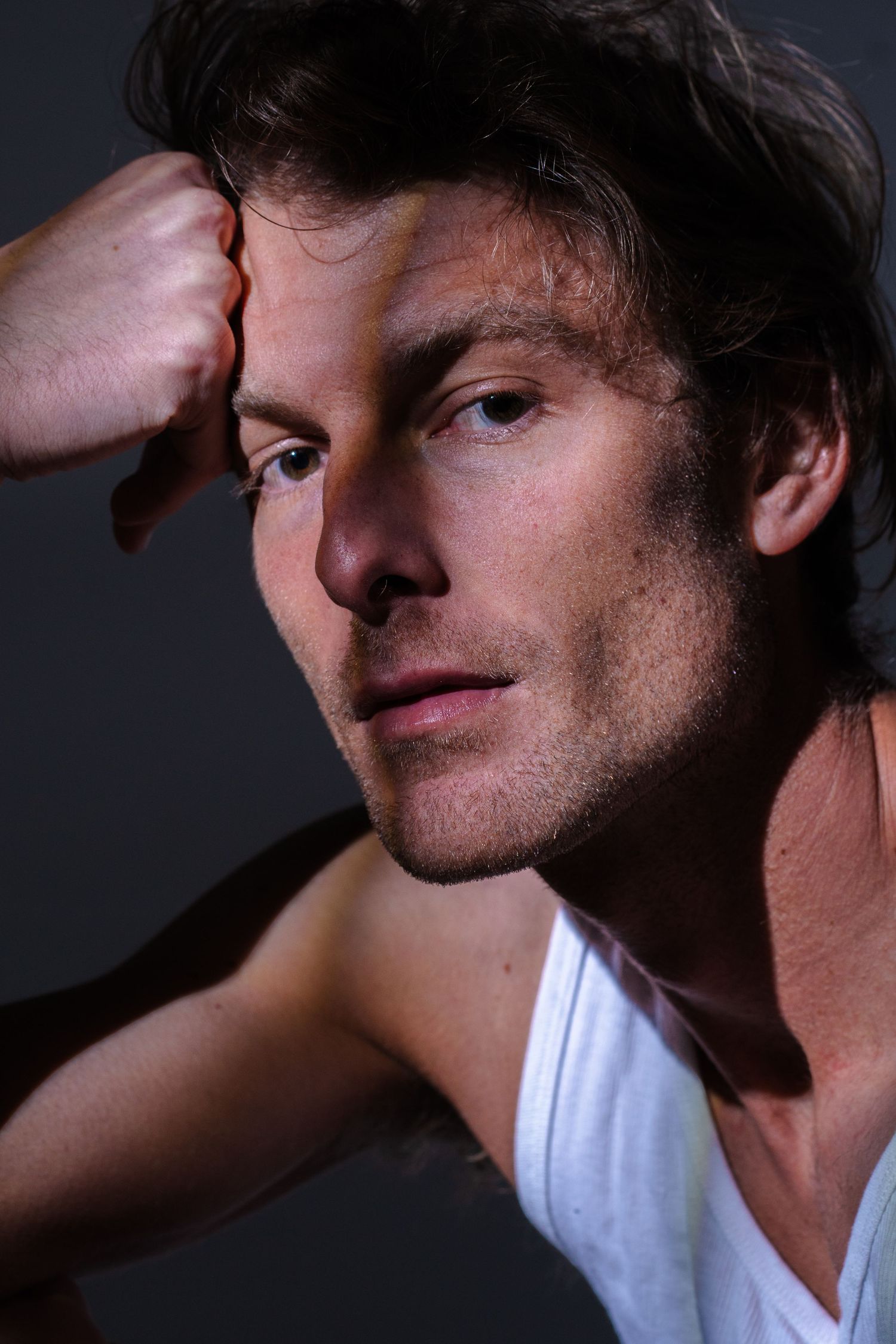 Artistic headshots with dramatic side lighting creating moody shadows on a subject in white.