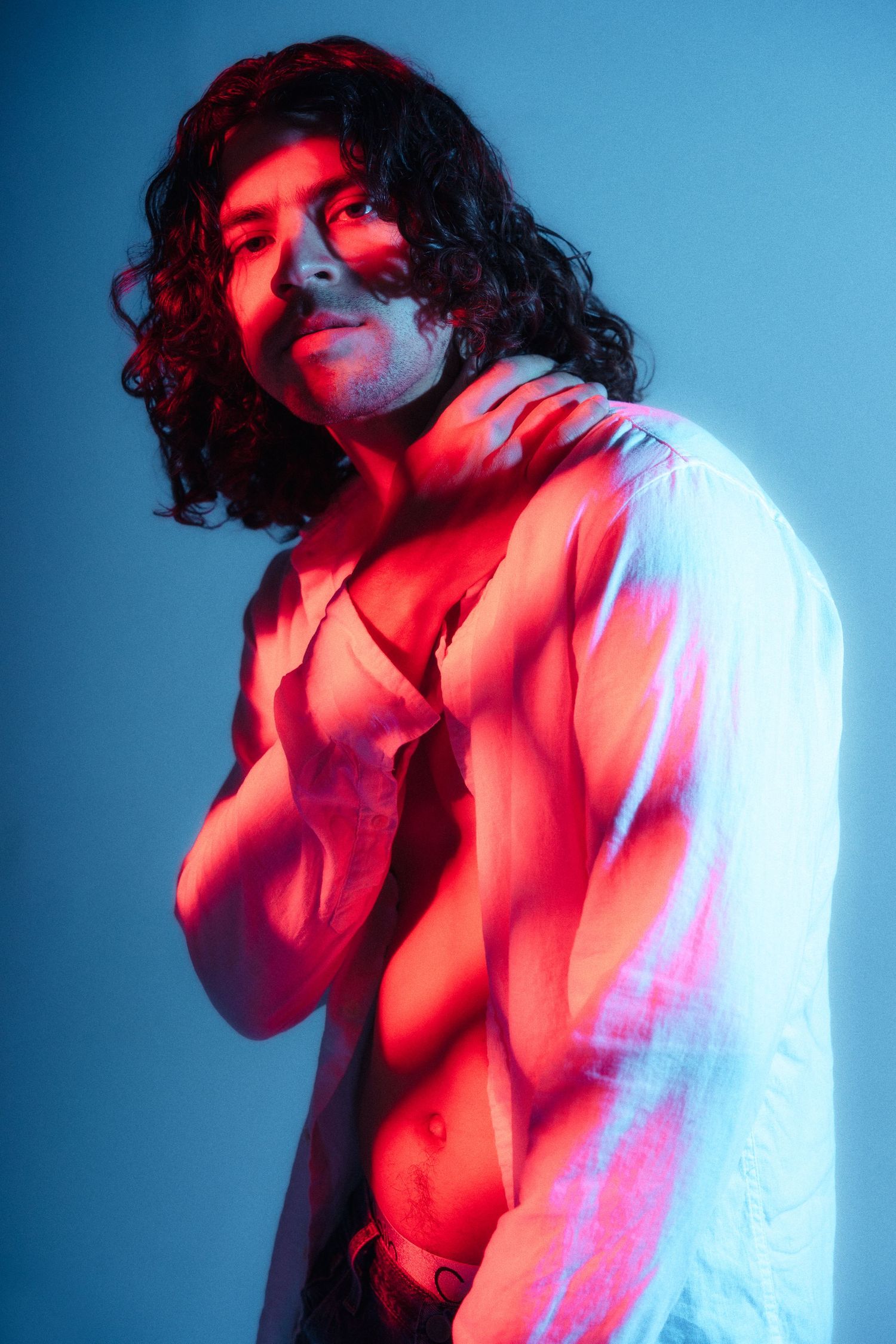 Artistic portrait with red and blue lighting effects against blue background.