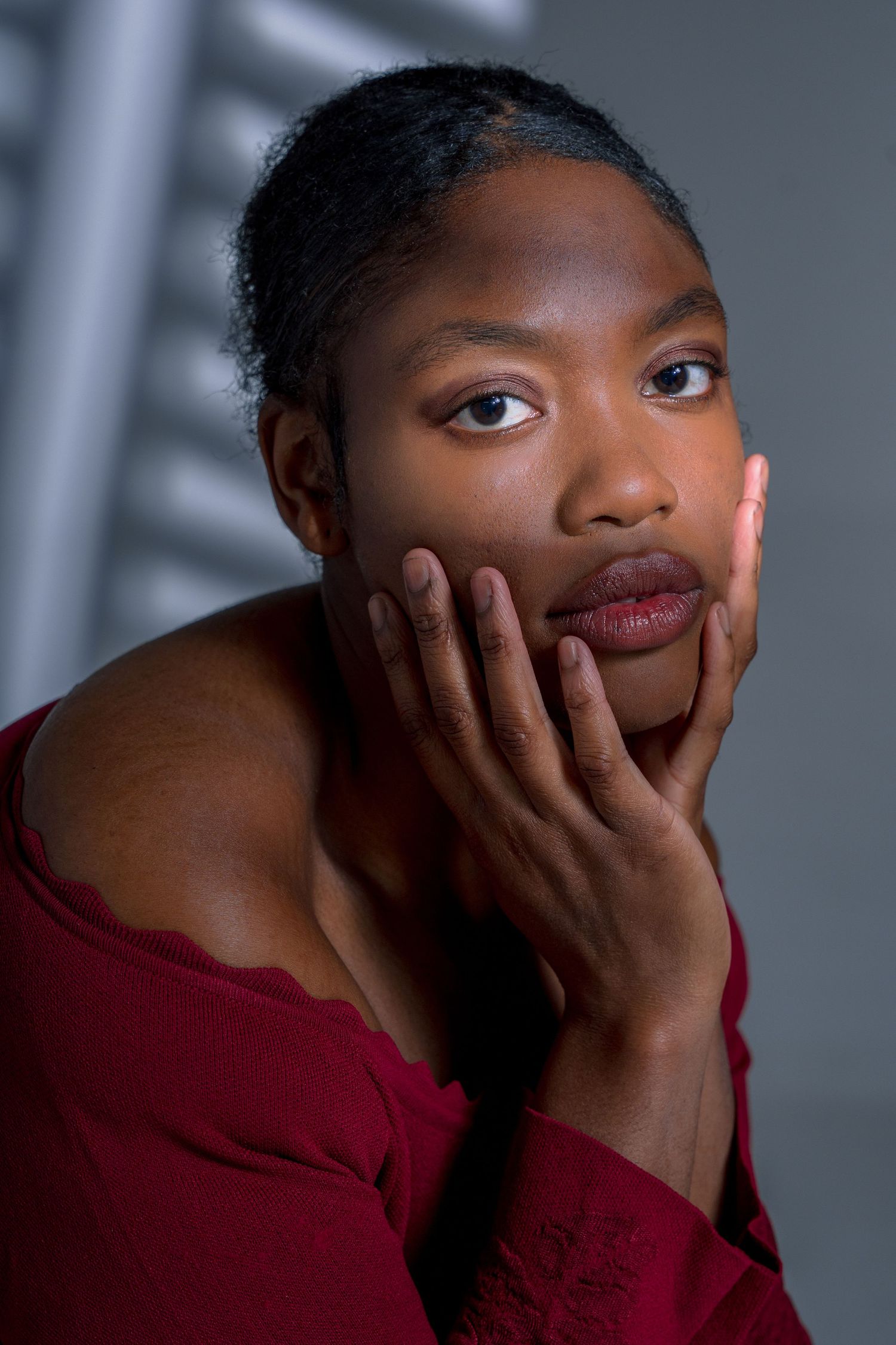 Expressive portrait sequence showing contemplative poses in burgundy against grey backdrop.