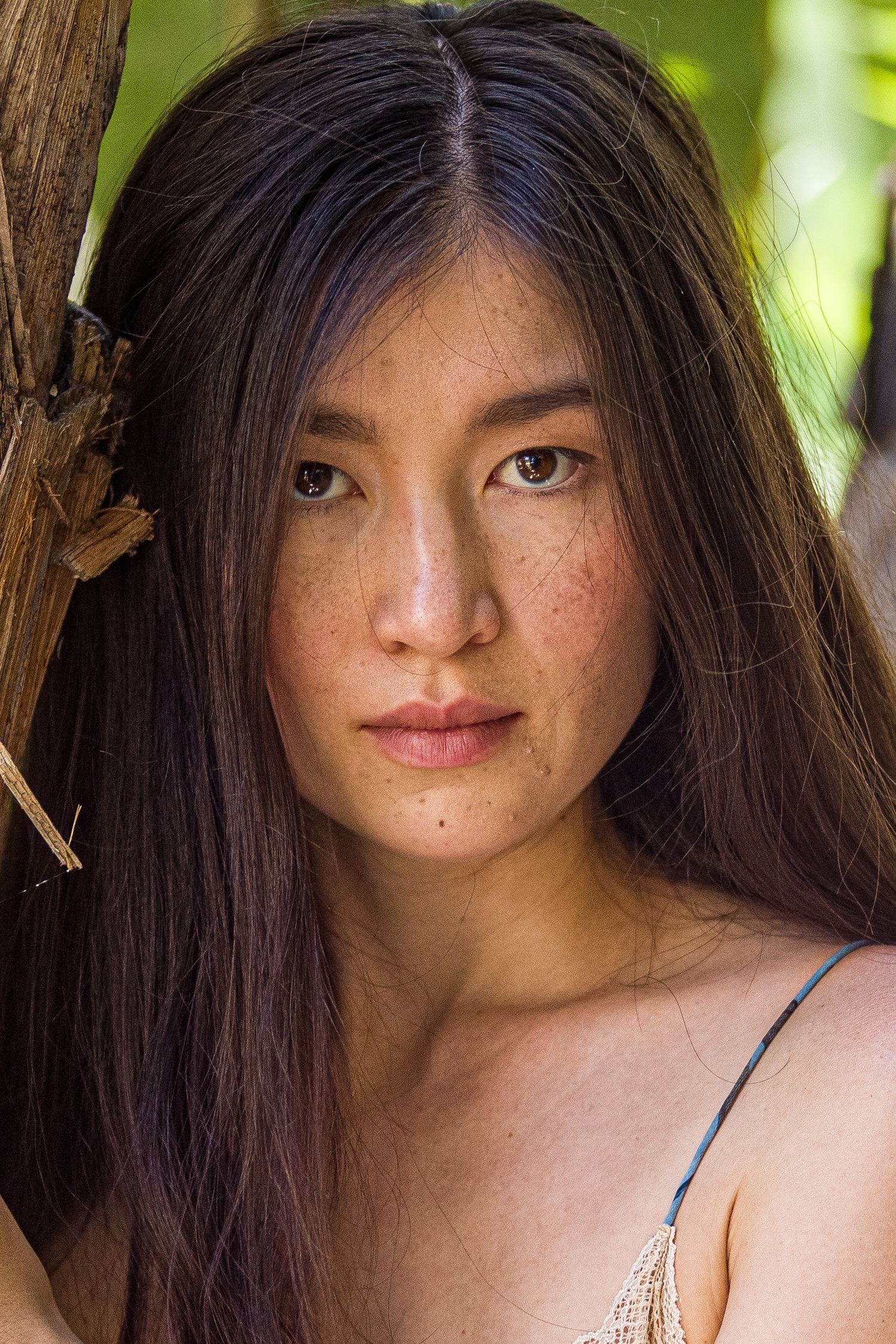Portrait with soft natural lighting and blurred green foliage background.