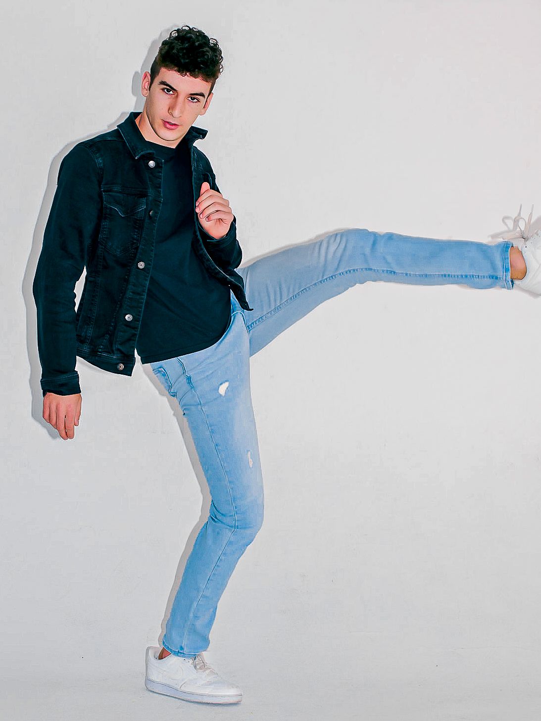 Dynamic sequence of someone performing high kicks while wearing jeans and a dark jacket.